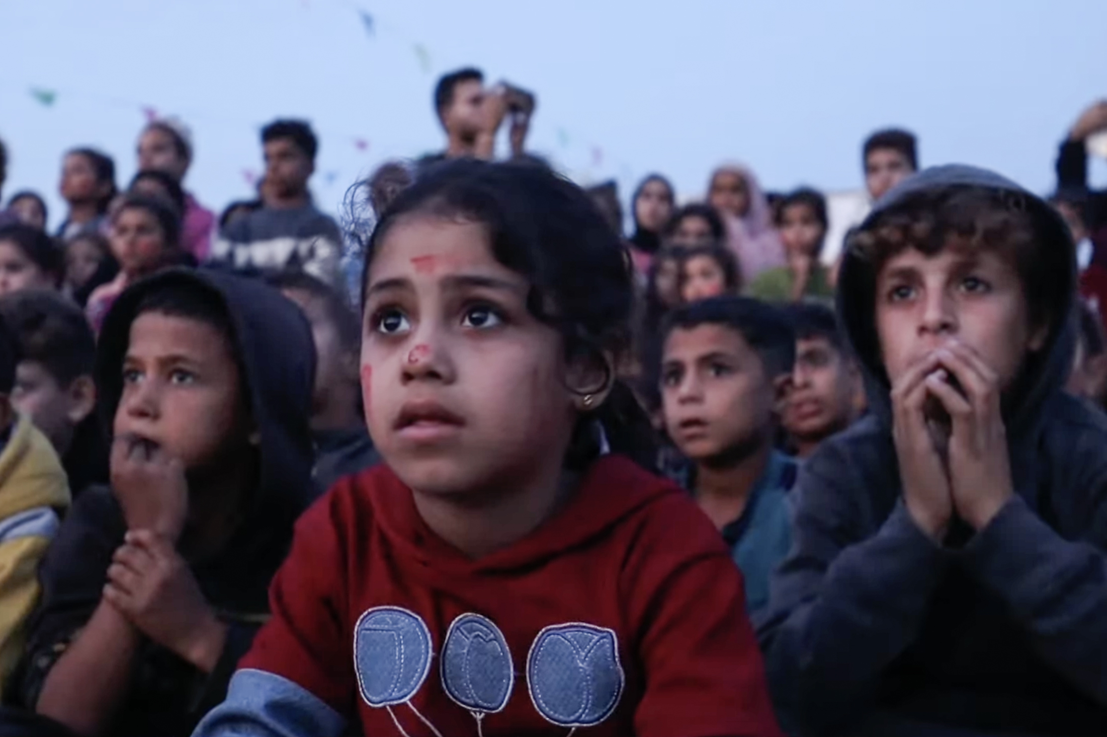 Children watch a film during an outdoor screening in Gaza City