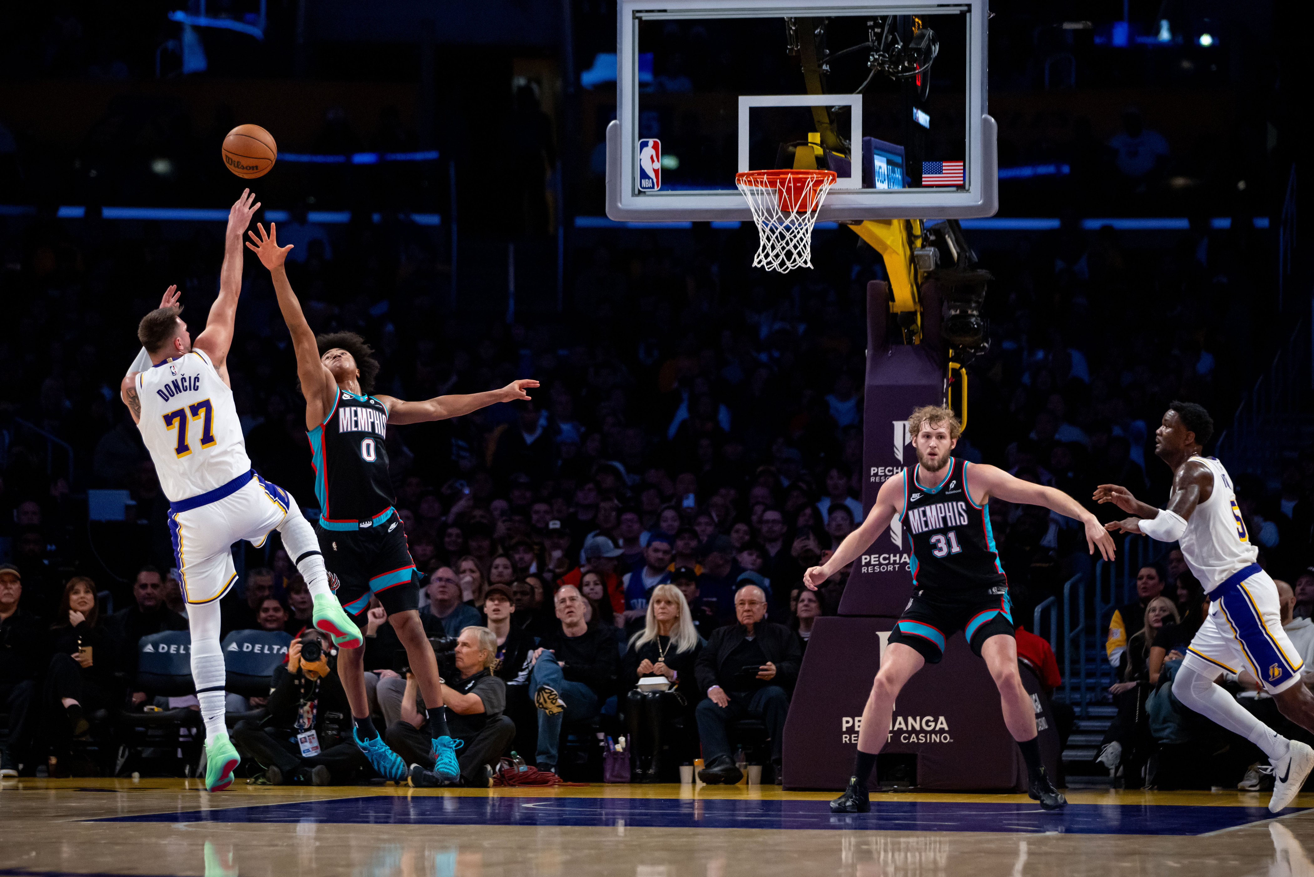 Luka Doncic (77), de los Lakers de Los Ángeles, dispara de larga distancia frente a Jaylen Wells (0), de los Grizzlies de Memphis, durante la primera mitad del juego de baloncesto de la NBA, el domingo 4 de enero de 2026, en Los Ángeles. (AP Foto/Ethan Swope)