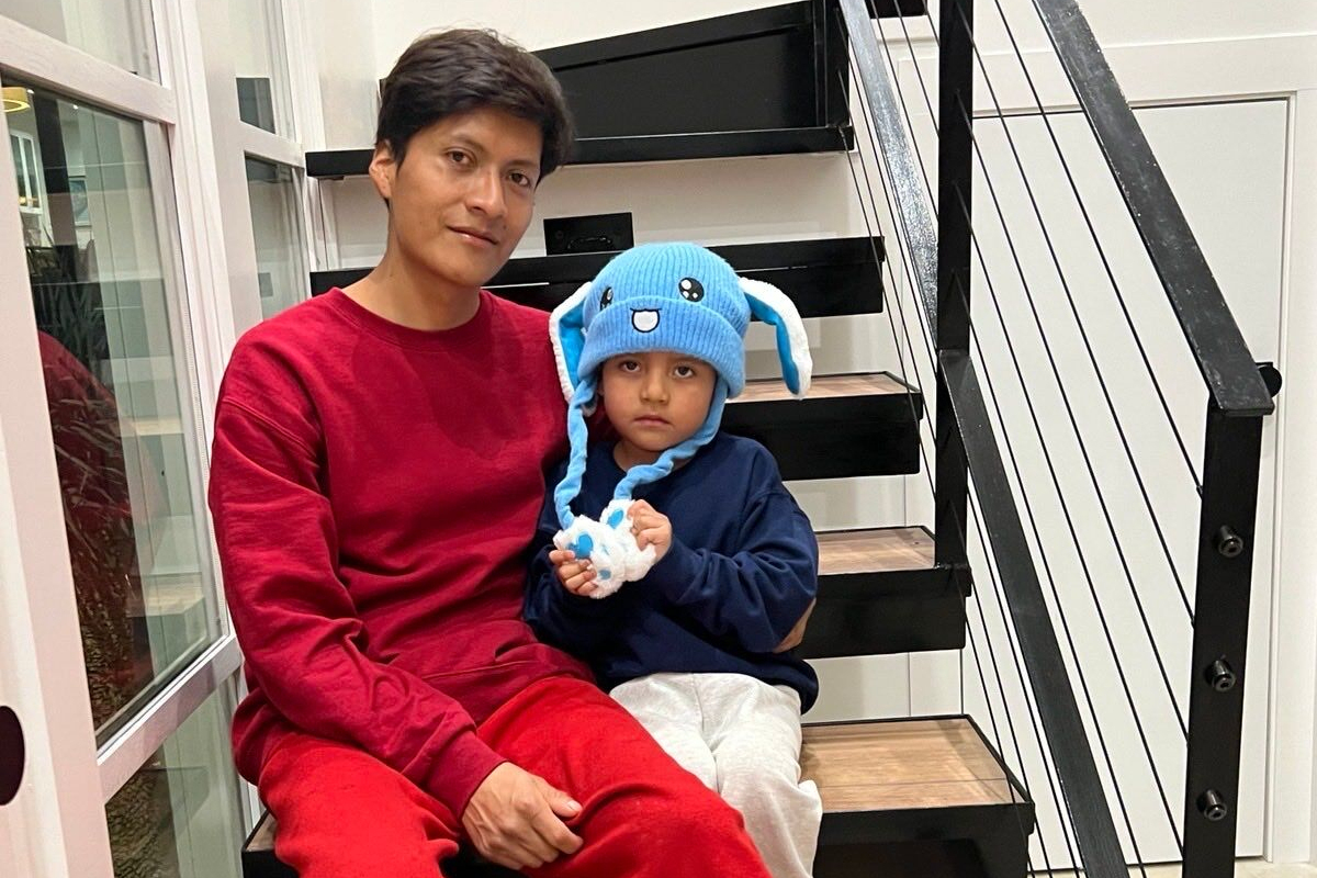 Adrian Conejo Arias sits with his son, Liam, who wears blue bunny ears