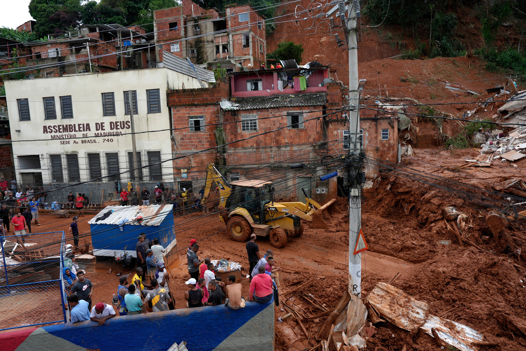 Firefighters and civil defence workers help at a site where homes collapsed due to heavy rains and severe flooding in the Parque Burnier neighbourhood of Juiz de Fora on February 24