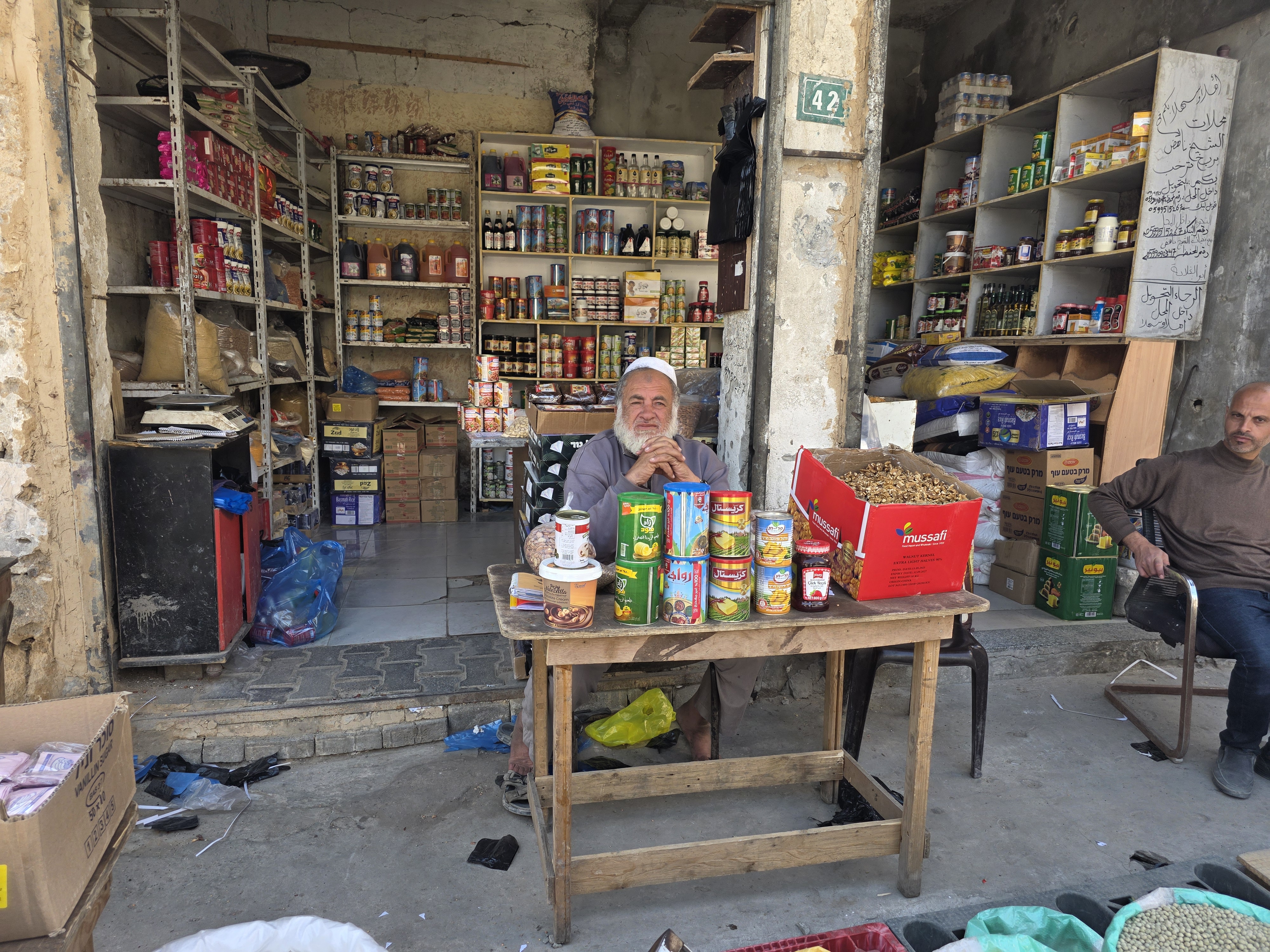 Nahed Barbakh, a 60-year-old shop owner and trader, sits at a table in front of his store