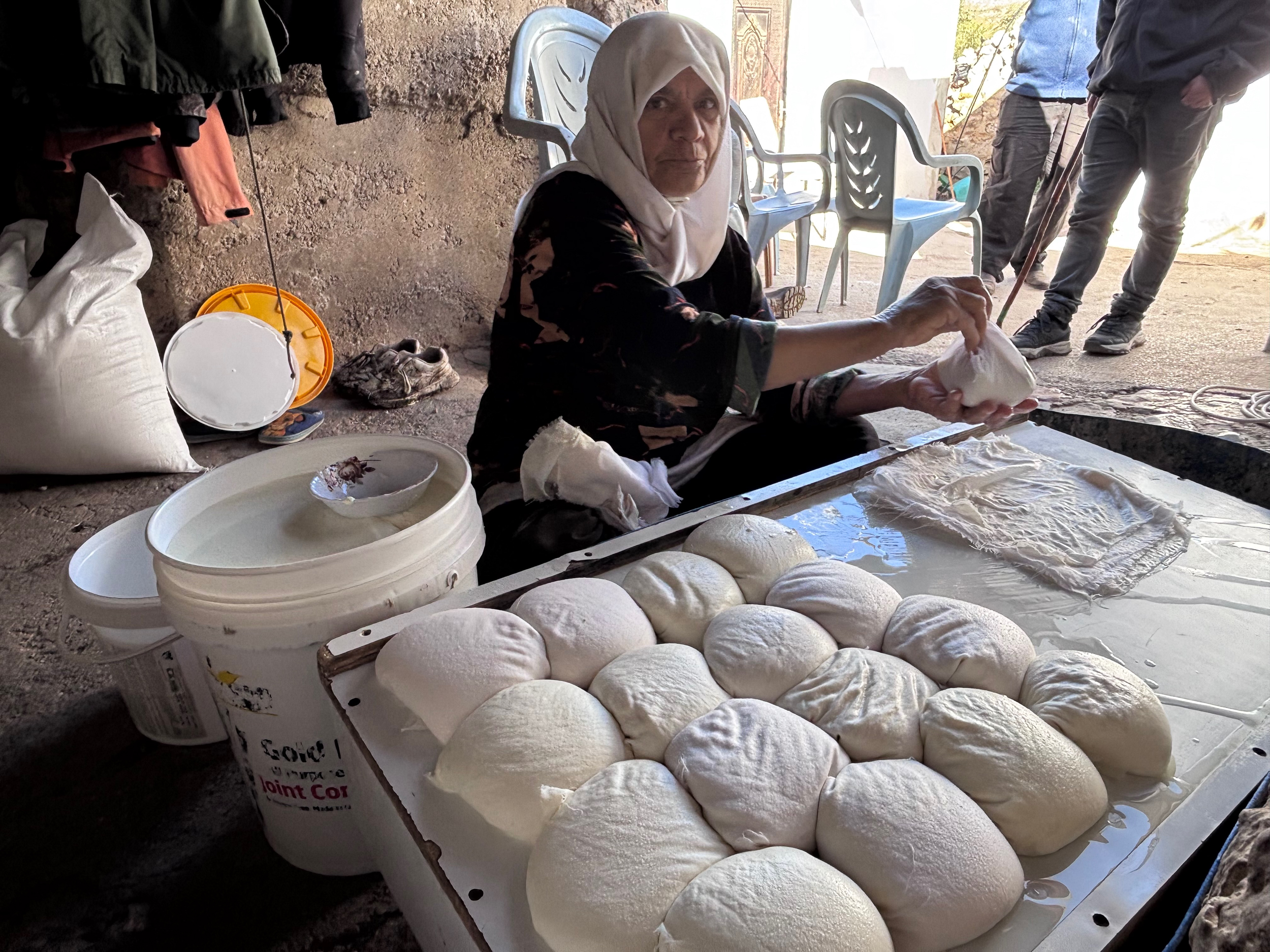 Hajja Latifa prepares baladi cheese in the courtyard of the Masallam family home in Khirbet al-Marajim [Al Jazeera]