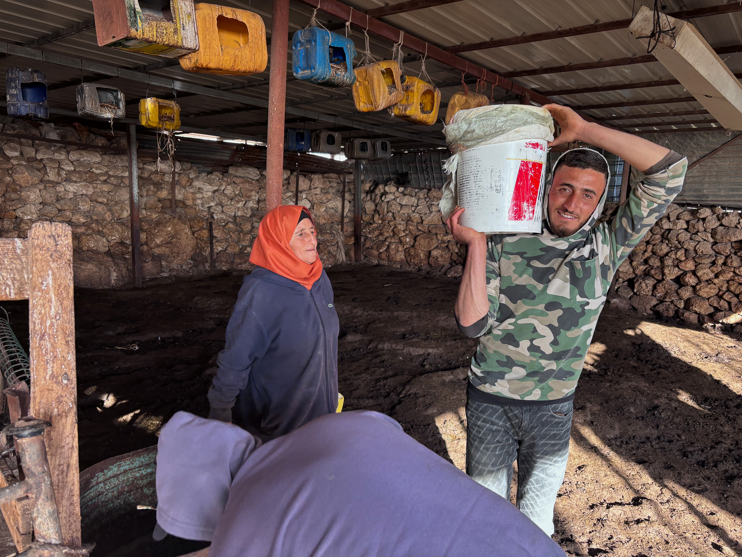 Thabet (R), Maysoon and Muhammad carry buckets of fresh milk after the morning milking [Al Jazeera]
