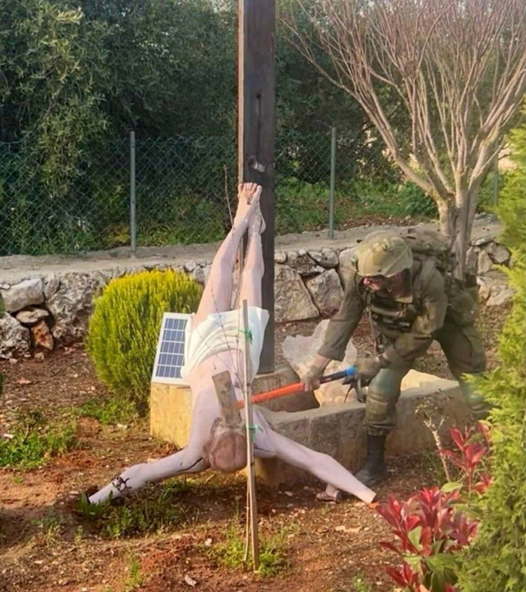 An Israeli soldier damages the head of a statue of Jesus.