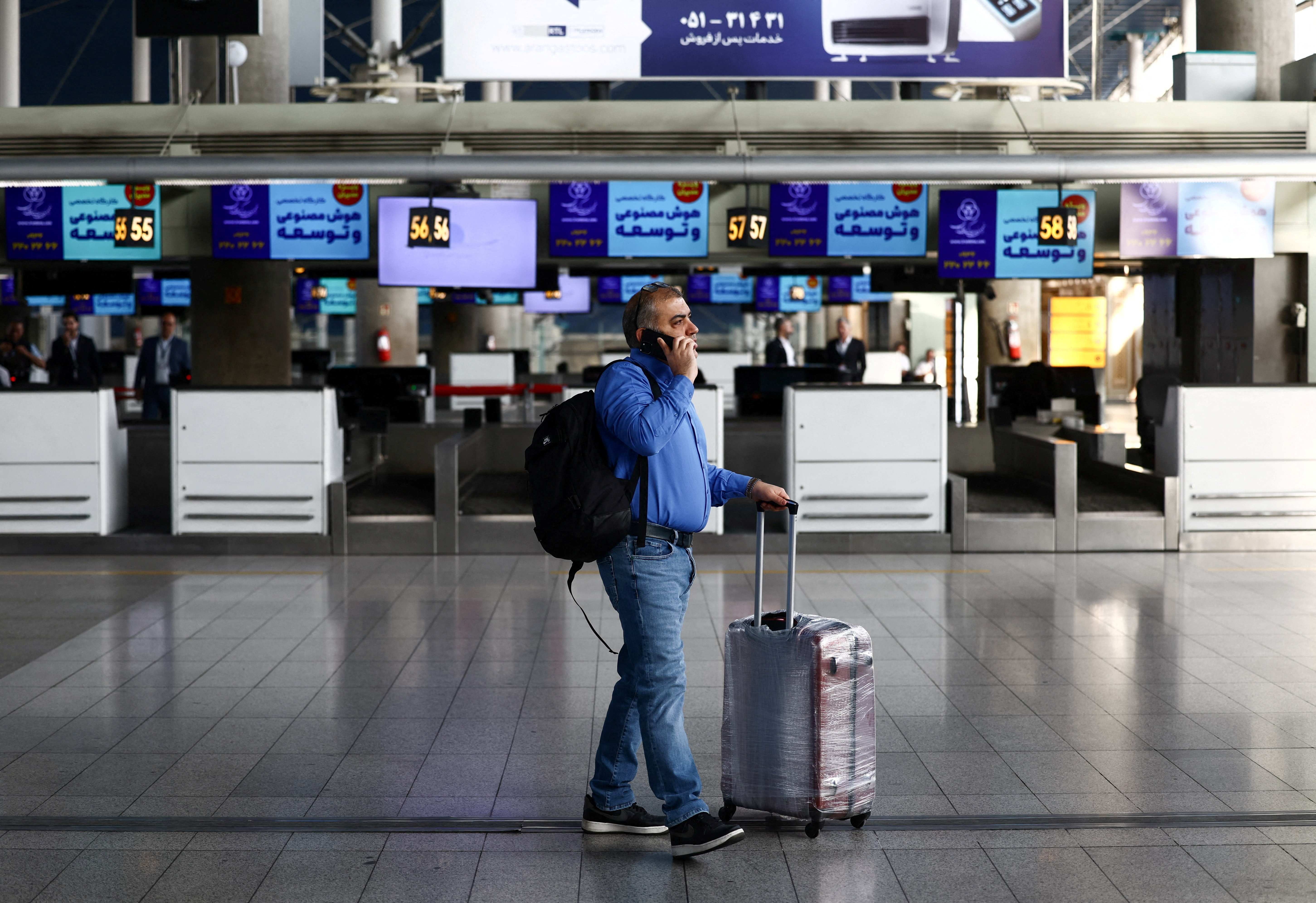 A passenger walks through an airport terminal hall.