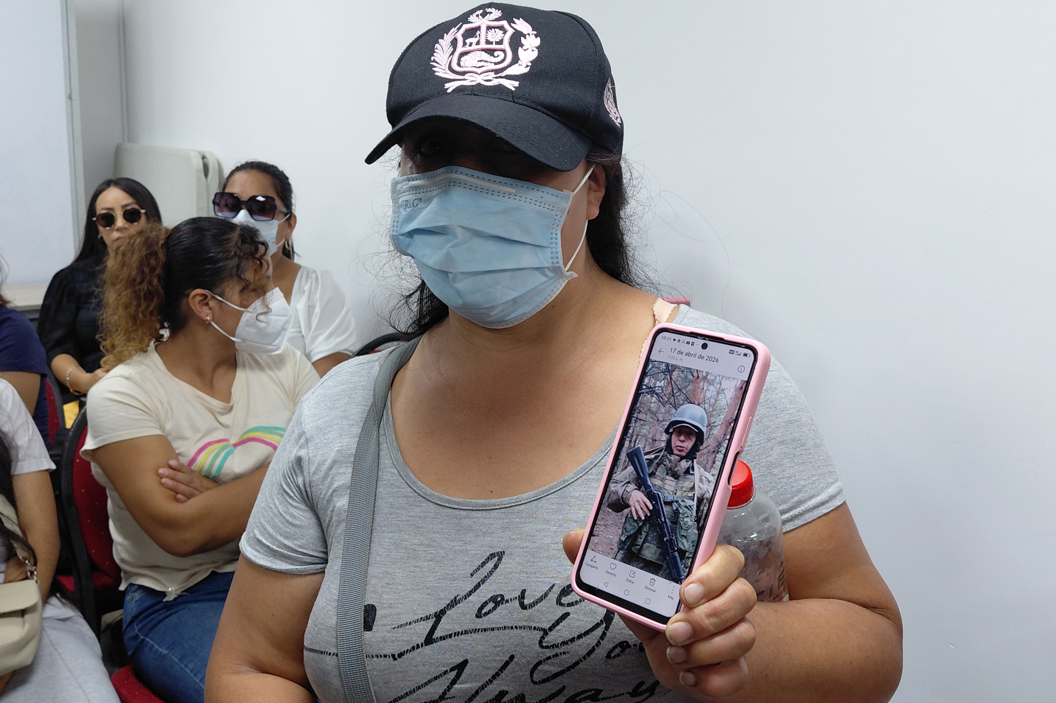 epa12920711 A woman shows a photo of her husband, a Peruvian citizen currently fighting in the war in Ukraine,