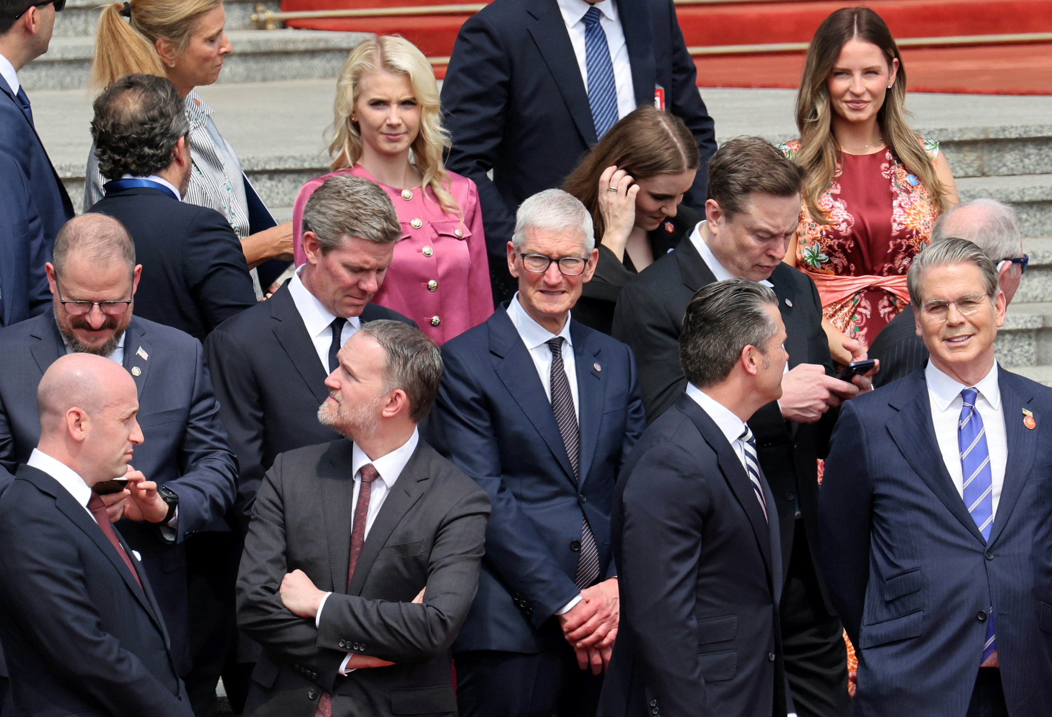 U.S. Treasury Secretary Scott Bessent, Defense Secretary Pete Hegseth, Trade Representative Jamieson Greer, White House Deputy Chief of Staff Stephen Miller, Tesla CEO Elon Musk, Apple CEO Tim Cook and other members of the U.S. delegation stand before the welcome ceremony for U.S. President Donald Trump, at the Great Hall of the People in Beijing, China May 14, 2026. REUTERS/Maxim Shemetov/Pool