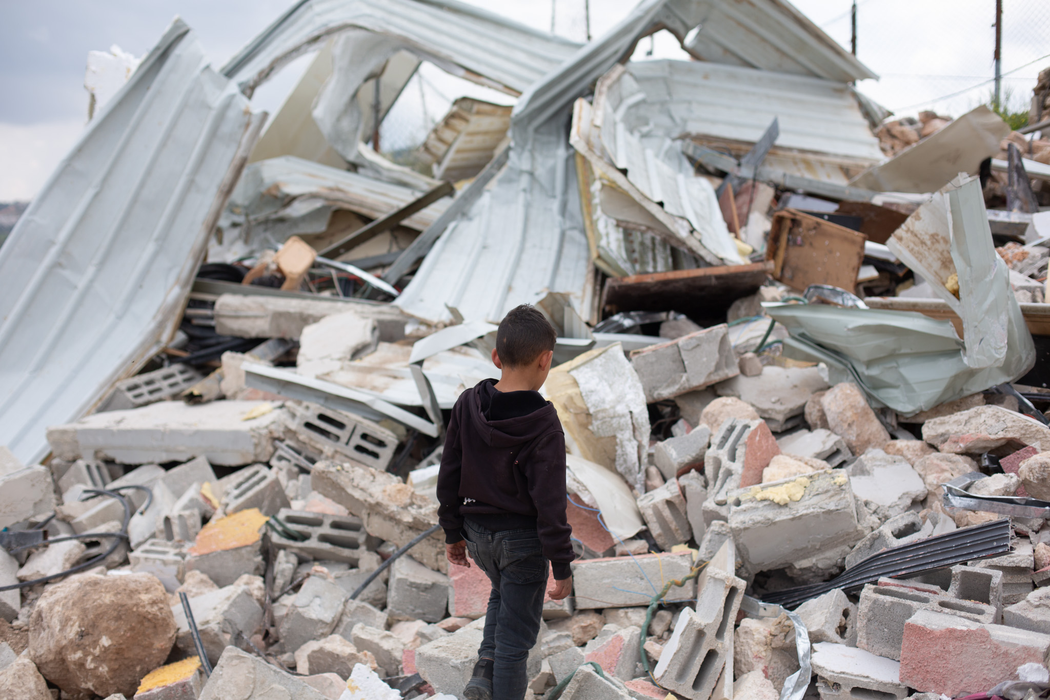 A young boy walks through the rubble of Professor Muhammad Masallam’s family home [Al Jazeera]