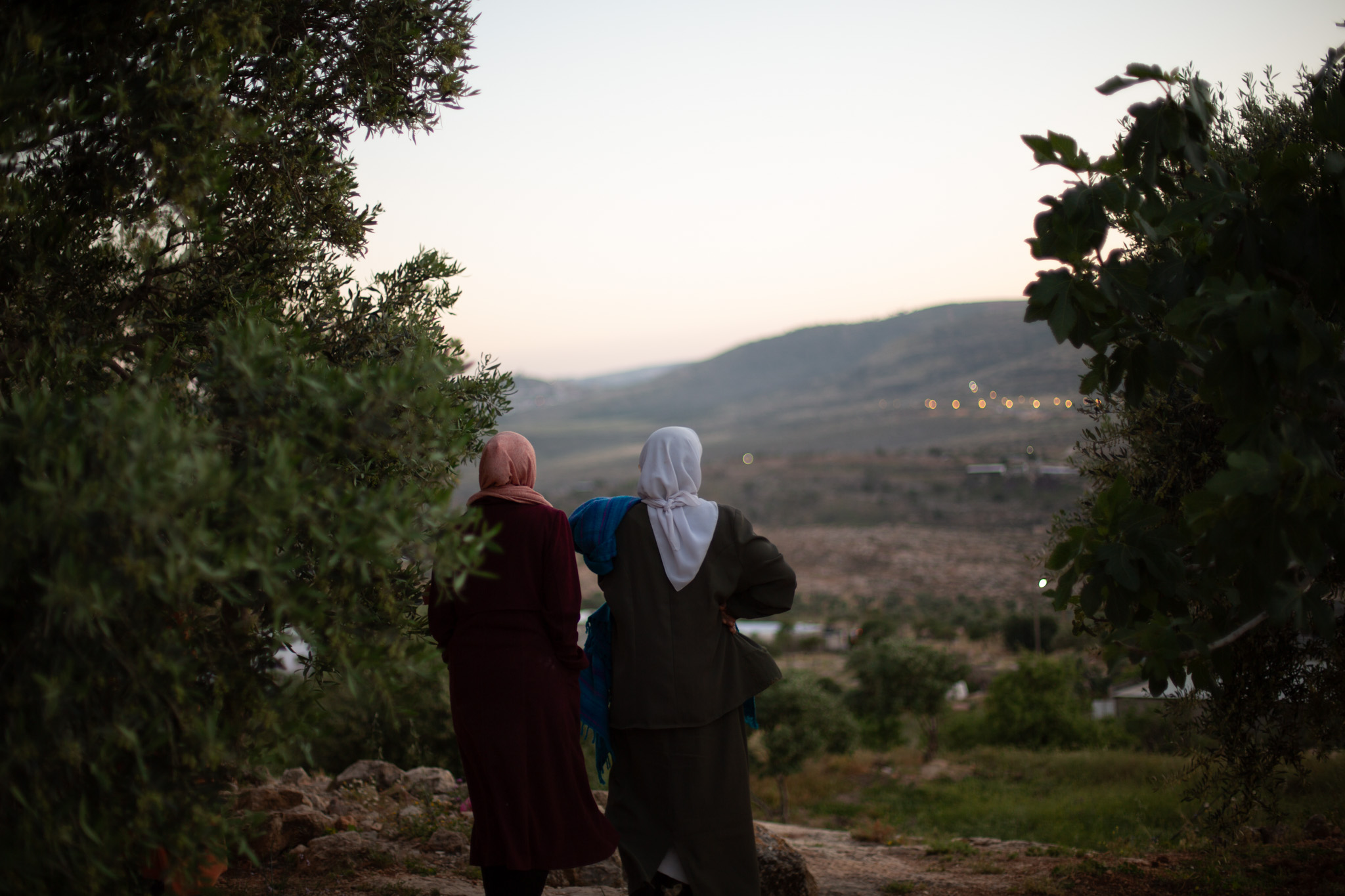 Hajja Latifa (R) and Maysoon Musallam look on as an ATV drives on the small roads near their home [Al Jazeera]