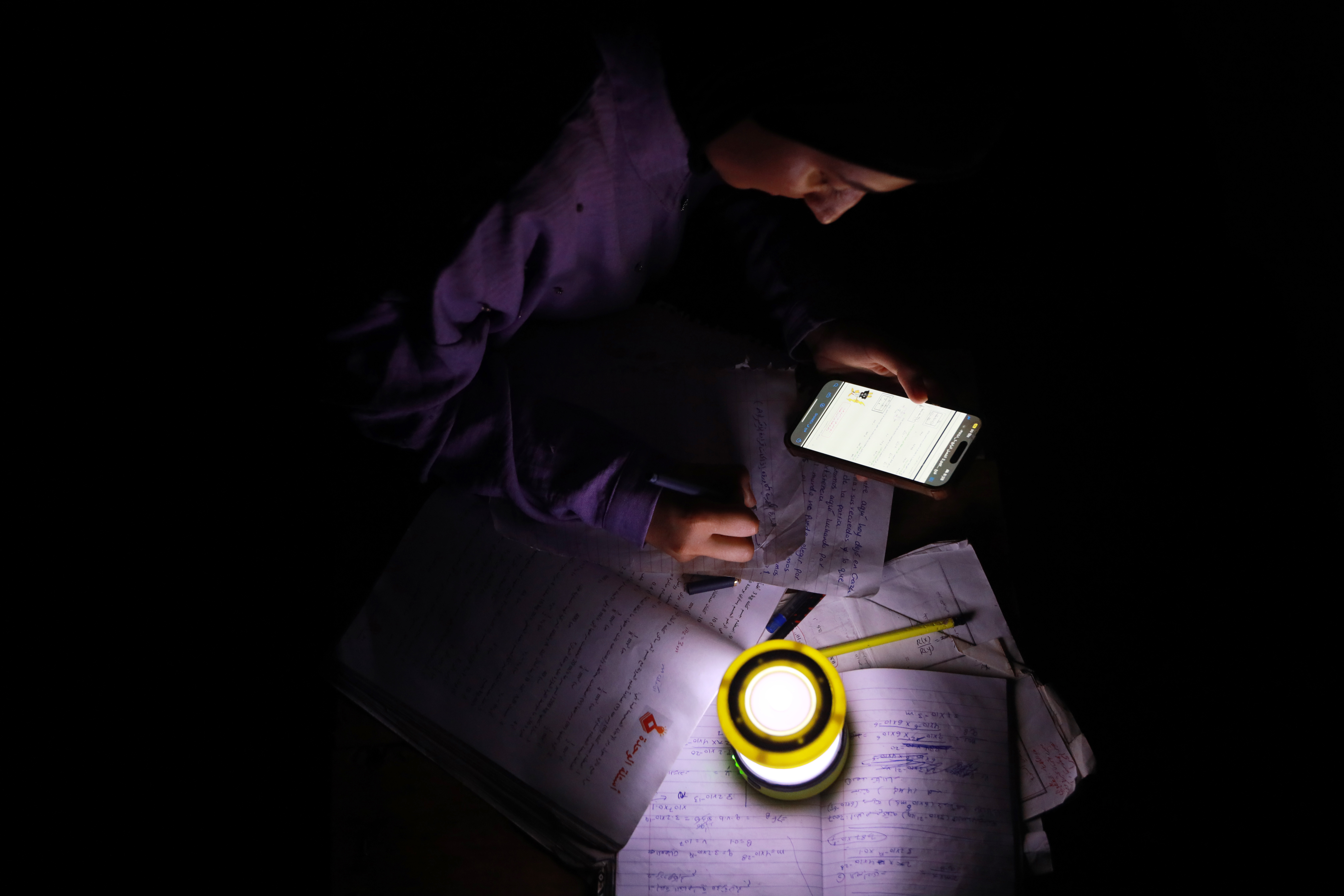 Dana Shabat studies by the light of the only flashlight in their tent