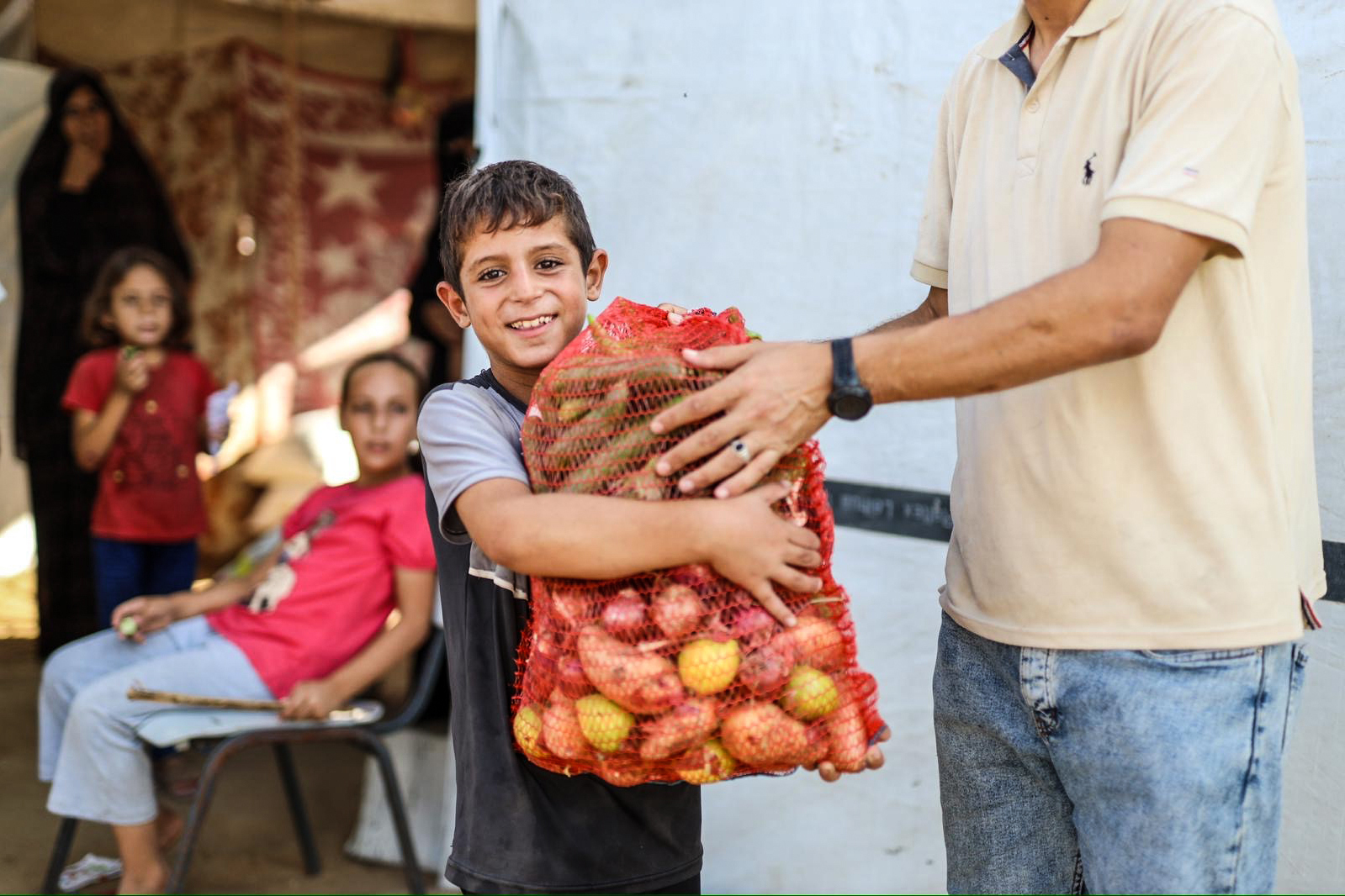 A displaced boy from Shujaiya, Gaza, receives fresh fruits and vegetables from UHR