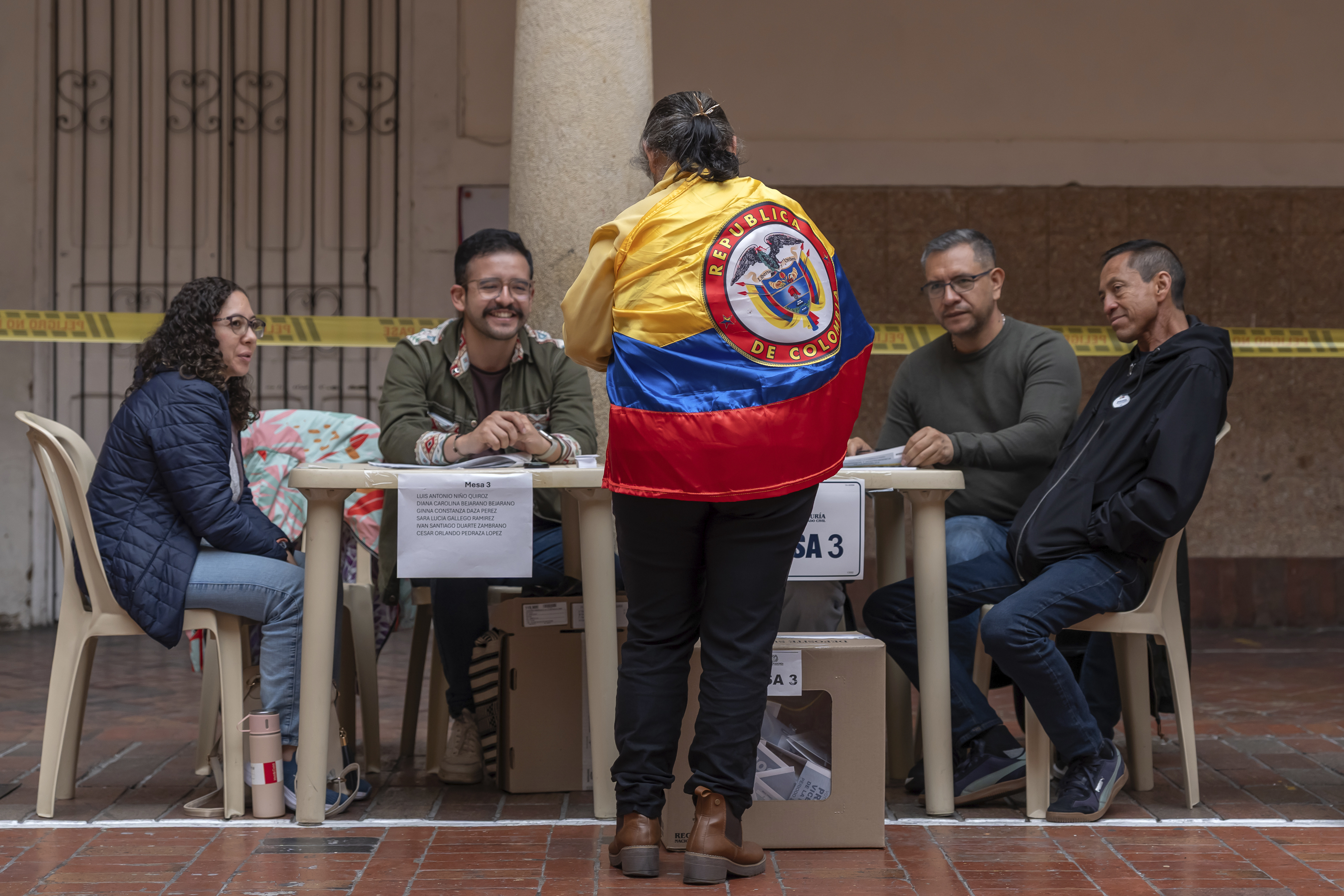 A woman wearing a Colombian flag registers to cast her vote.