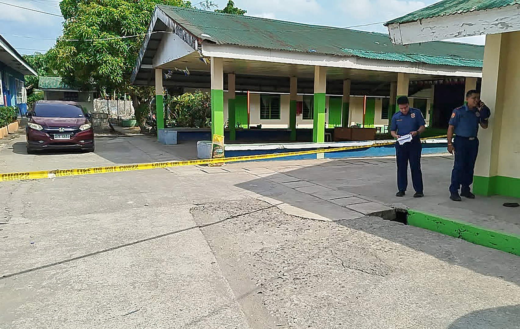 Policemen stand near the crime scene of a school compound after a shooting incident at a high school compound in Tacloban City, Leyte province on June 22, 2026. [NOEL SIANOSA/AFP]