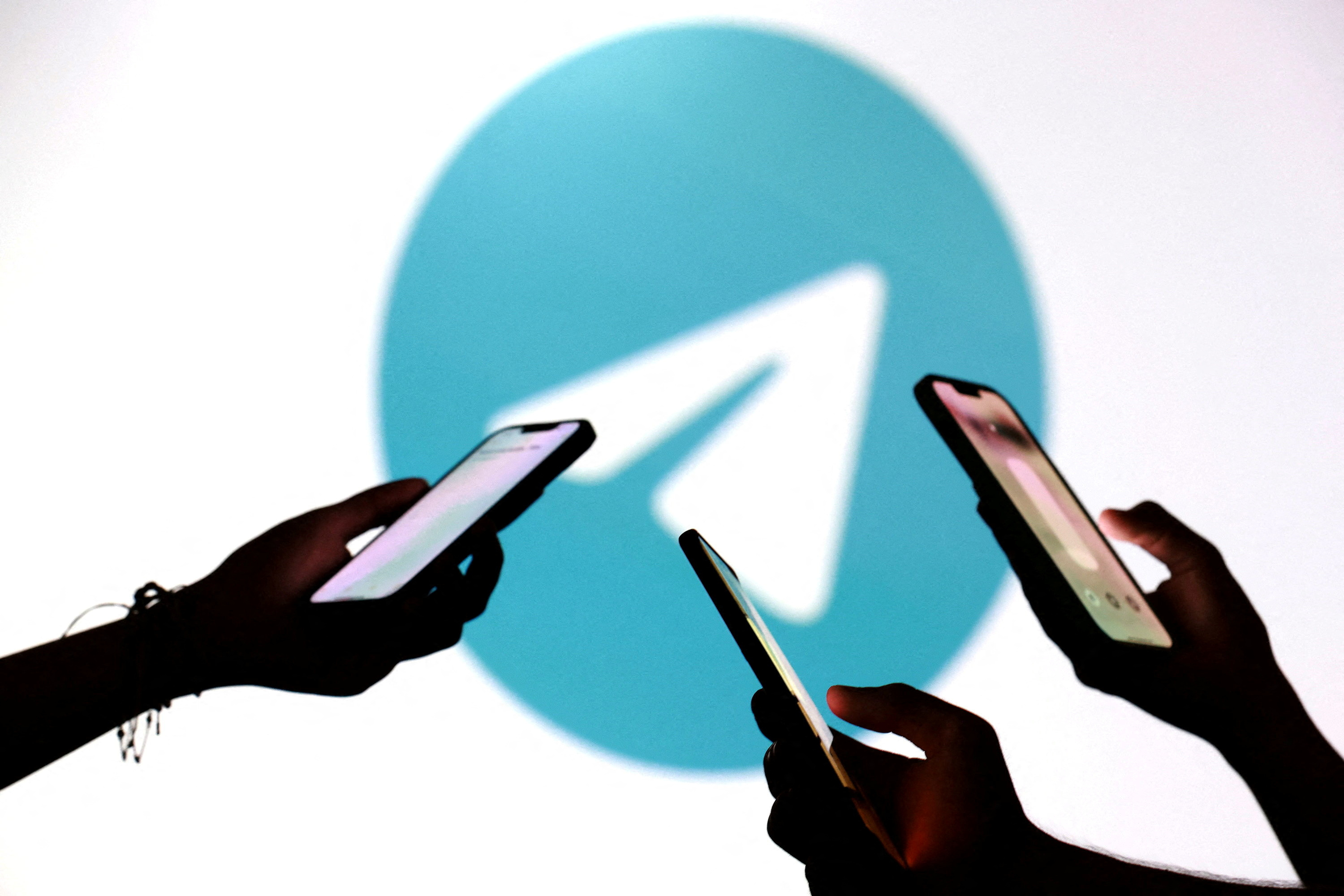 FILE PHOTO: Teenagers pose for a photo while holding smartphones in front of a Telegram logo in this illustration taken September 11, 2025. REUTERS/Dado Ruvic/Illustration/File Photo