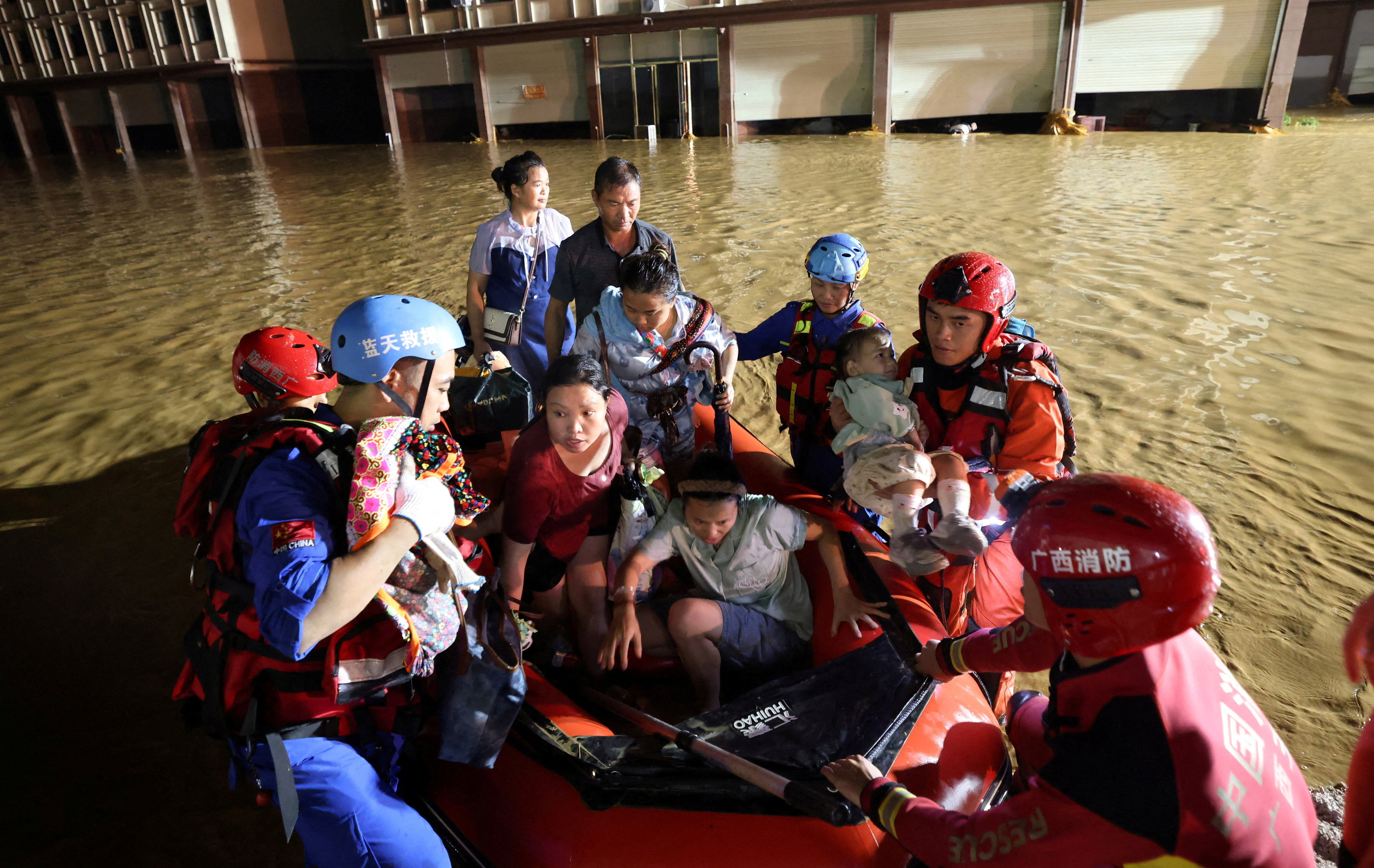 Rescue workers evacuate residents in a rubber dinghy after floodwaters inundate villages downstream of the Liulan Reservoir dam breach [China Out/Reuters]