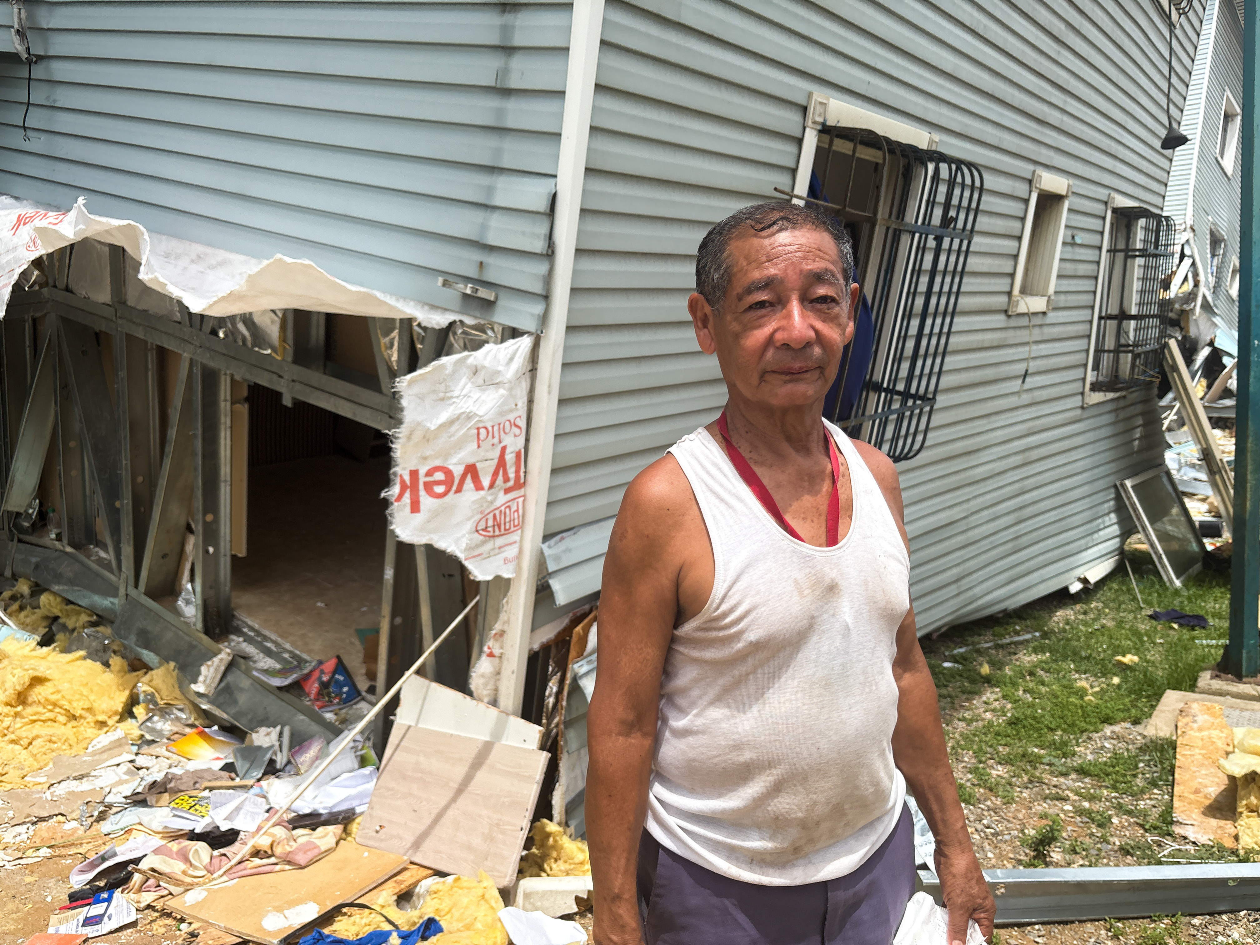 A man stands outside a destroyed government housing complex where he lived