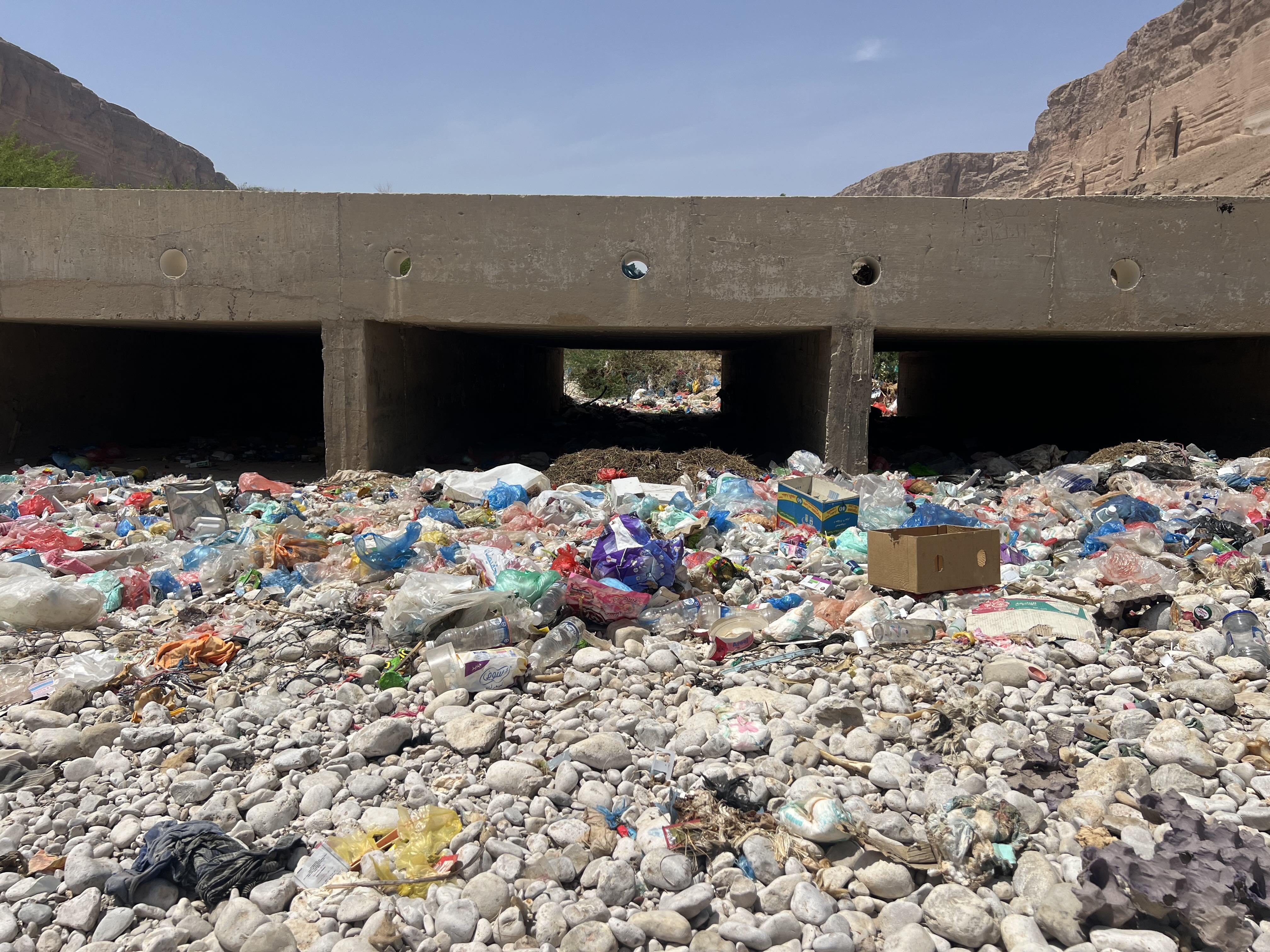 Plastic waste and household rubbish accumulate beneath a bridge in Wadi Daw’an, where residents say seasonal floods wash the debris into irrigation channels serving nearby farms. [Saeed Al-BatatiAl Jazeera]