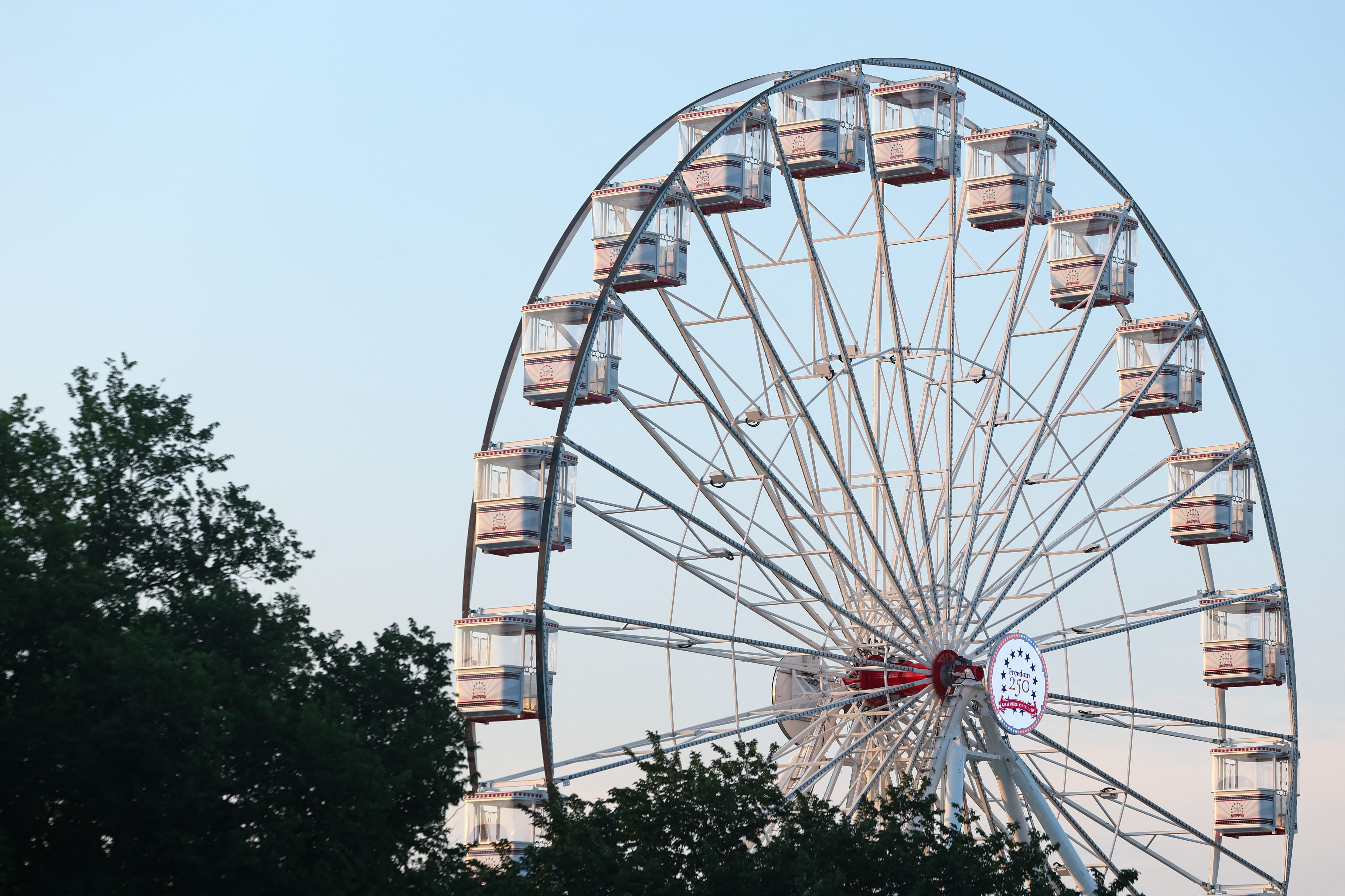 WASHINGTON, DC - JULY 04: The sun rises on the Freedom 250 Ferris wheel in The Great American State Fair on the National Mall on July 04, 2026 in Washington, DC. Numerous events, activities, and fireworks are planned in celebration of America's 250th Anniversary. Finn Gomez/Getty Images/AFP (Photo by Finn Gomez / GETTY IMAGES NORTH AMERICA / Getty Images via AFP)