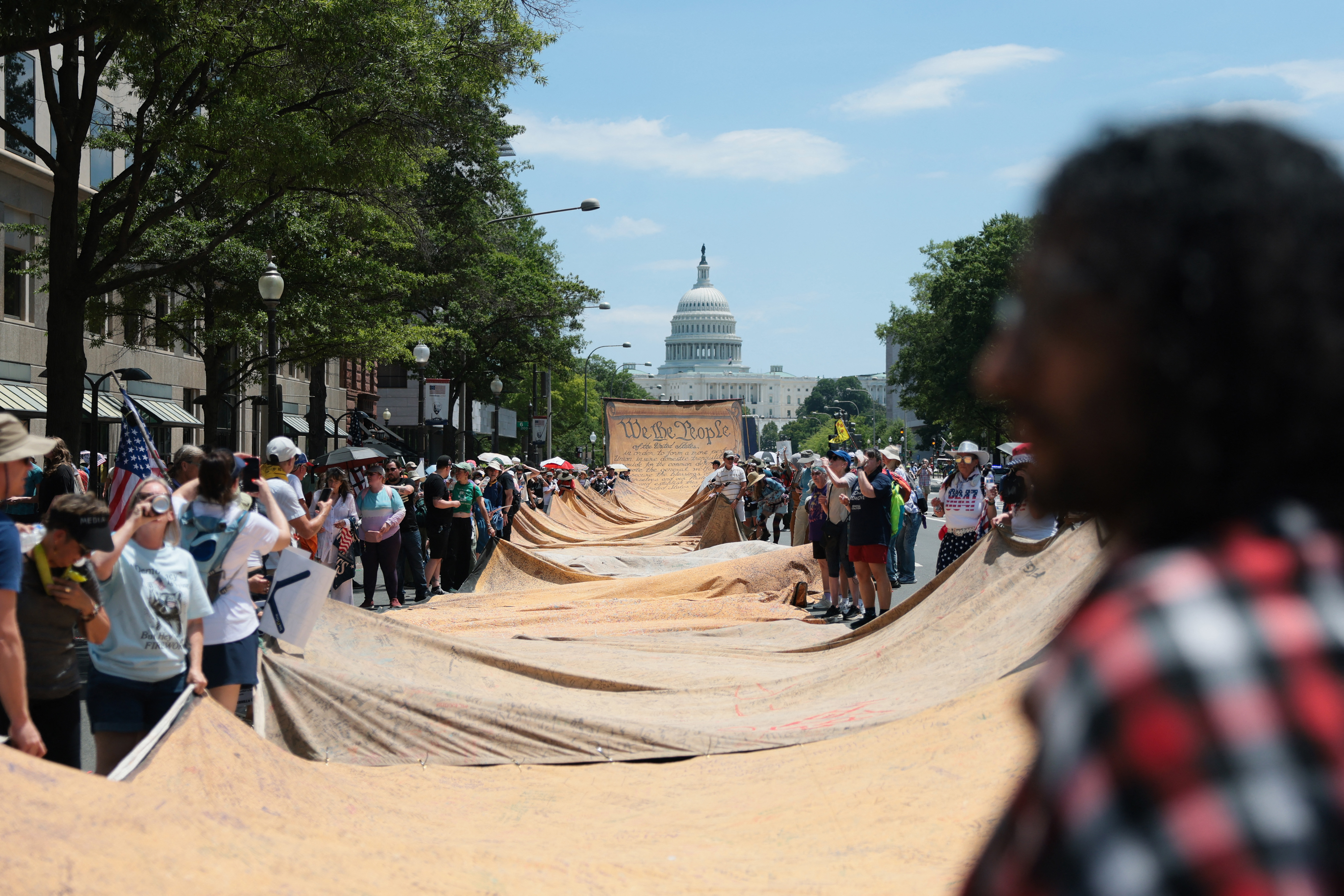 WASHINGTON, DC - JULY 04: Protesters carry a reproduction of the Declaration of Independence as they participate in a "We The People 250" march during Fourth of July celebrations on July 04, 2026 in Washington, DC. Numerous events, activities, and fireworks are planned in celebration of America's 250th Anniversary amidst an extreme heat wave bringing dangerous triple digit temperatures to much of the eastern United States. Joe Raedle/Getty Images/AFP (Photo by JOE RAEDLE / GETTY IMAGES NORTH AMERICA / Getty Images via AFP)