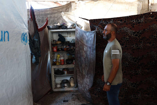 Nidal Rafeea, 40, uses his broken refrigerator as a cupboard to store canned food and kitchen supplies.[Abdelhakim Abu Riash/ Al Jazeera] 