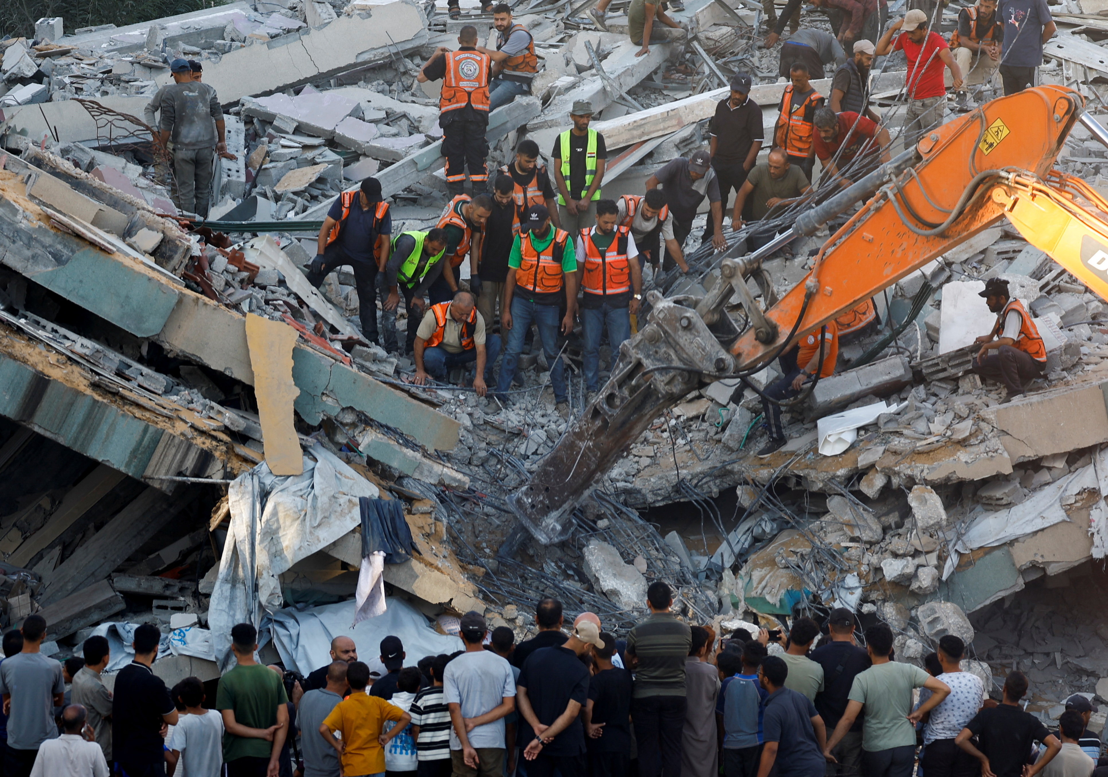 People gather as Civil Defence workers attempt to rescue those who are trapped beneath the rubble