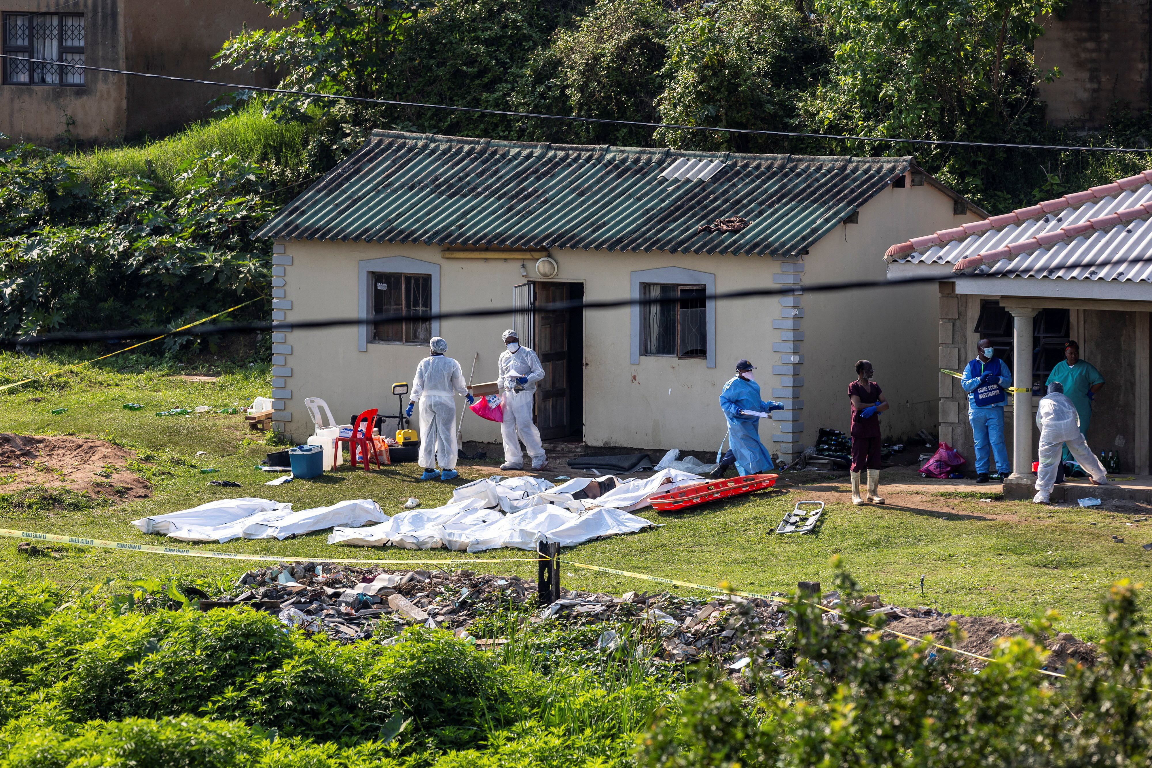 Police forensics personnel work at the scene where several people were killed and several others injured, in the township of KwaMakhutha near Durban, South Africa