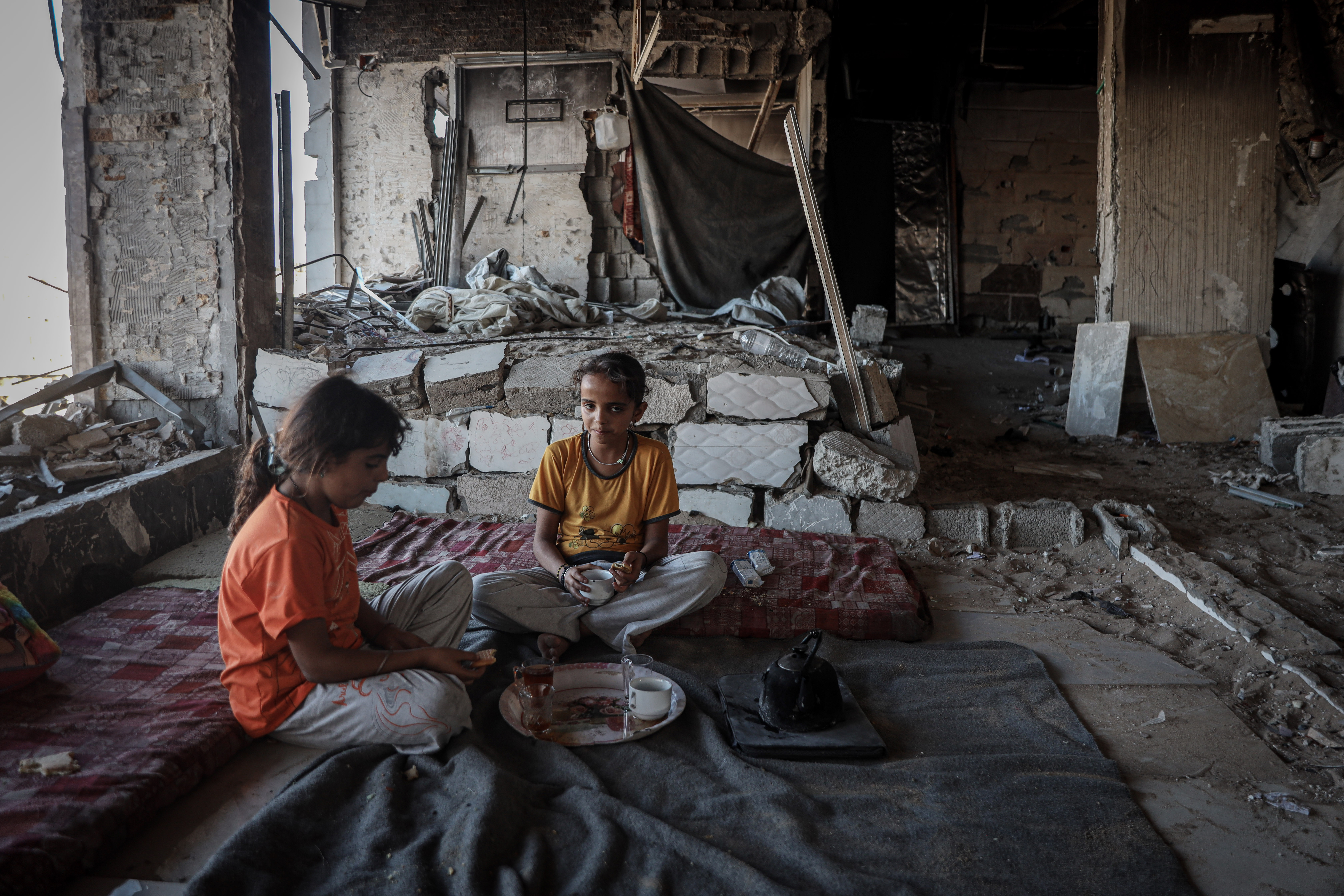 Islam’s daughters sit inside the room where they live in the Al Najma building, which is at risk of collapse.