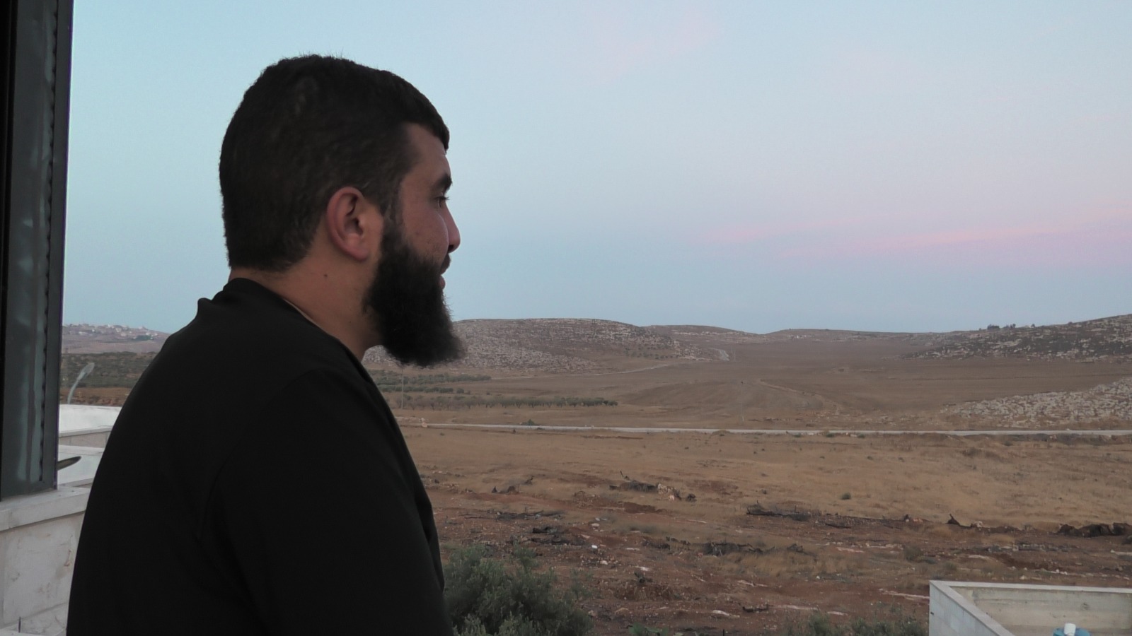 Bilal Abu Alia is standing in his balcony looking at his confiscated land