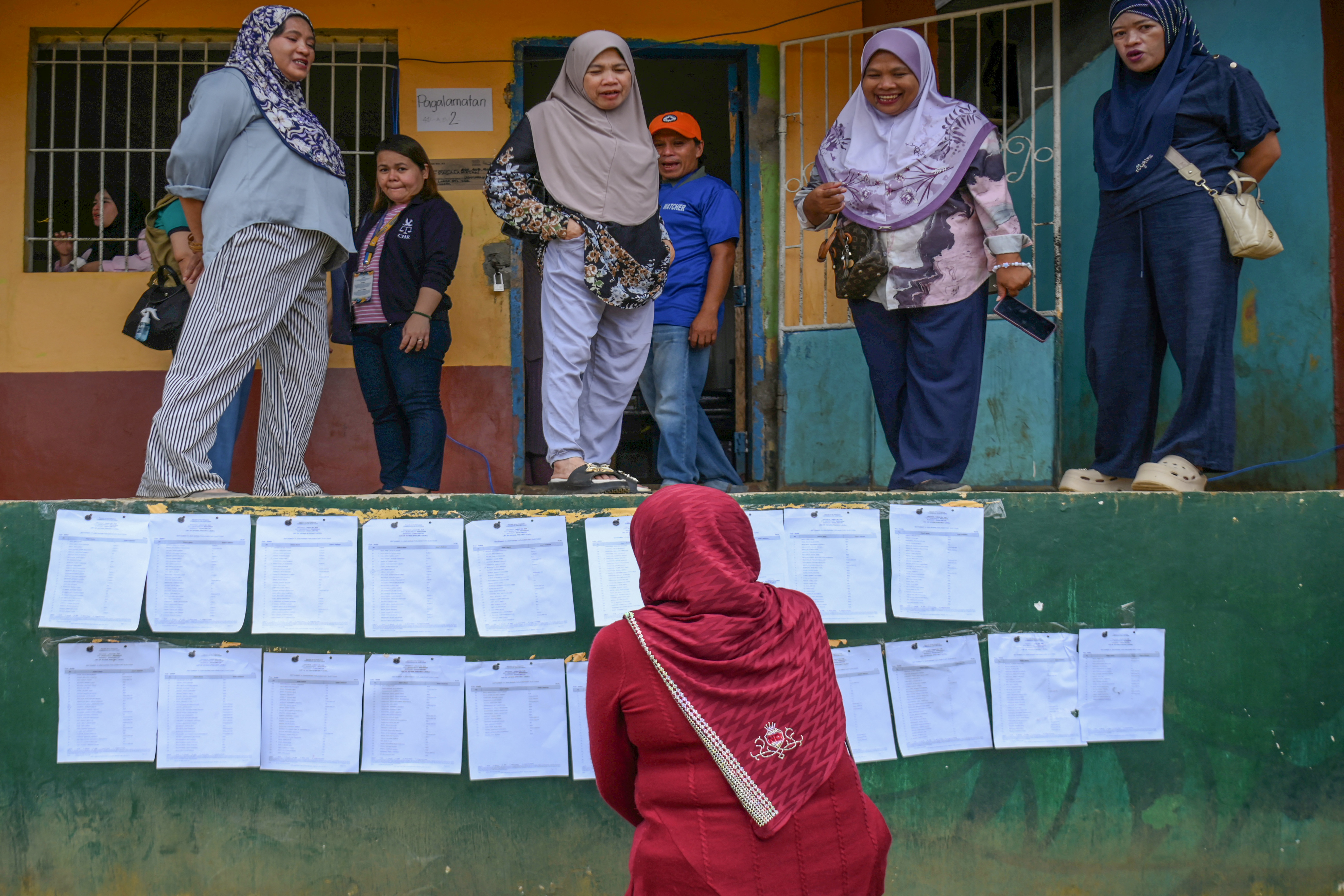 A voter looks for her precinct number posted on a wall.