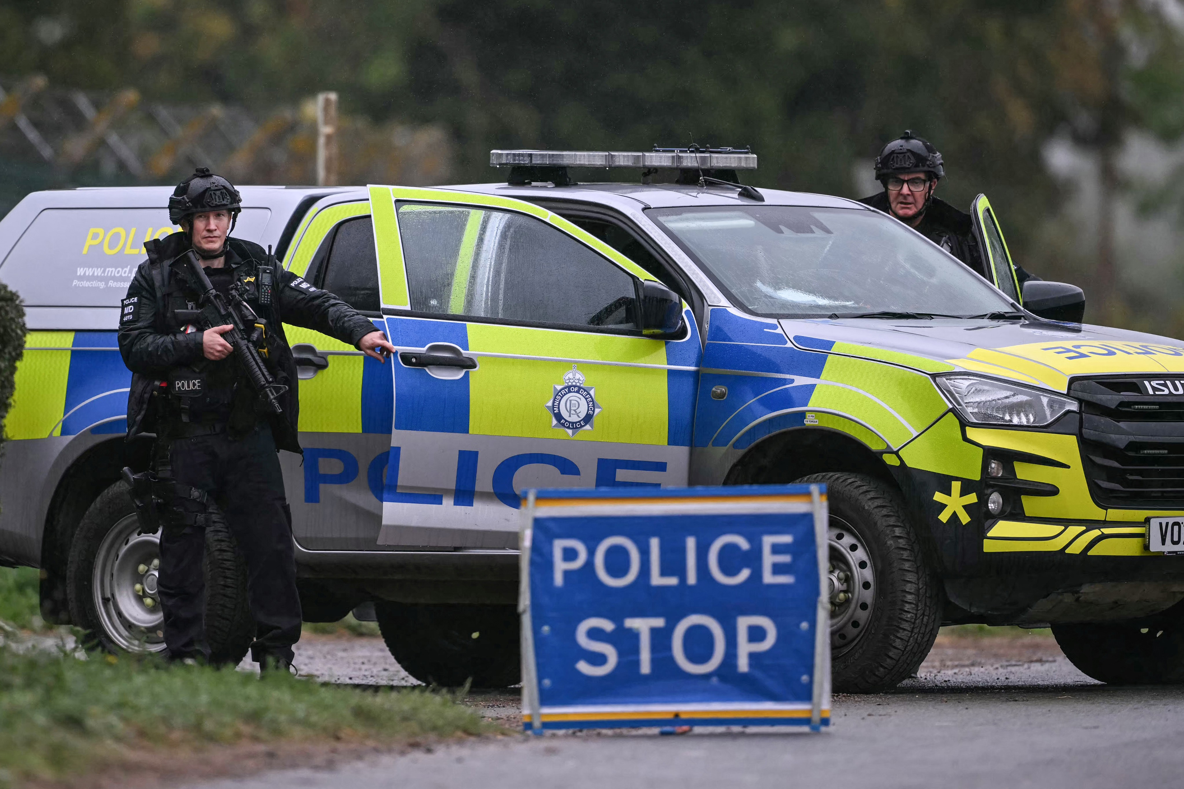 Armed police man a roadblock while posted outside RAF Fairford base in Fairford, south-west England on September 27, 2026, as UK counter-terrorism police investigate an incident near the base in the village of Whelford. British police on September 27 declared a major incident and evacuated villagers living near a base used by the US air force after arresting several men on suspicion of explosives offences. (Photo by JUSTIN TALLIS / AFP)