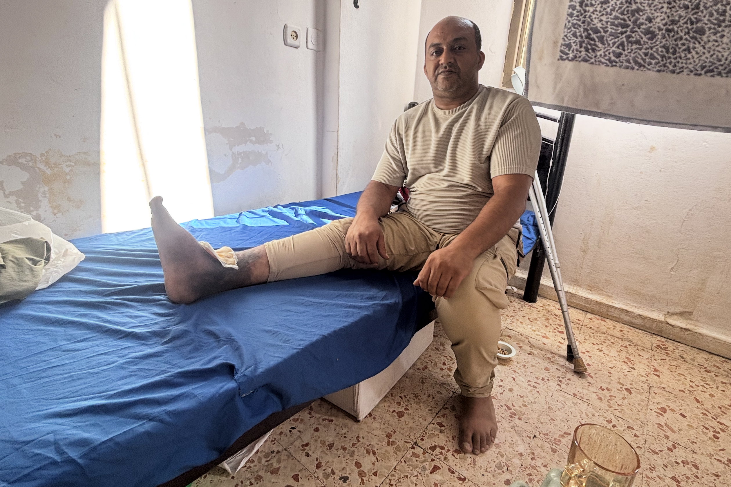 Hakim Mar’i in his family’s apartment with his injured leg, which prevents him from working [Al Jazeera]