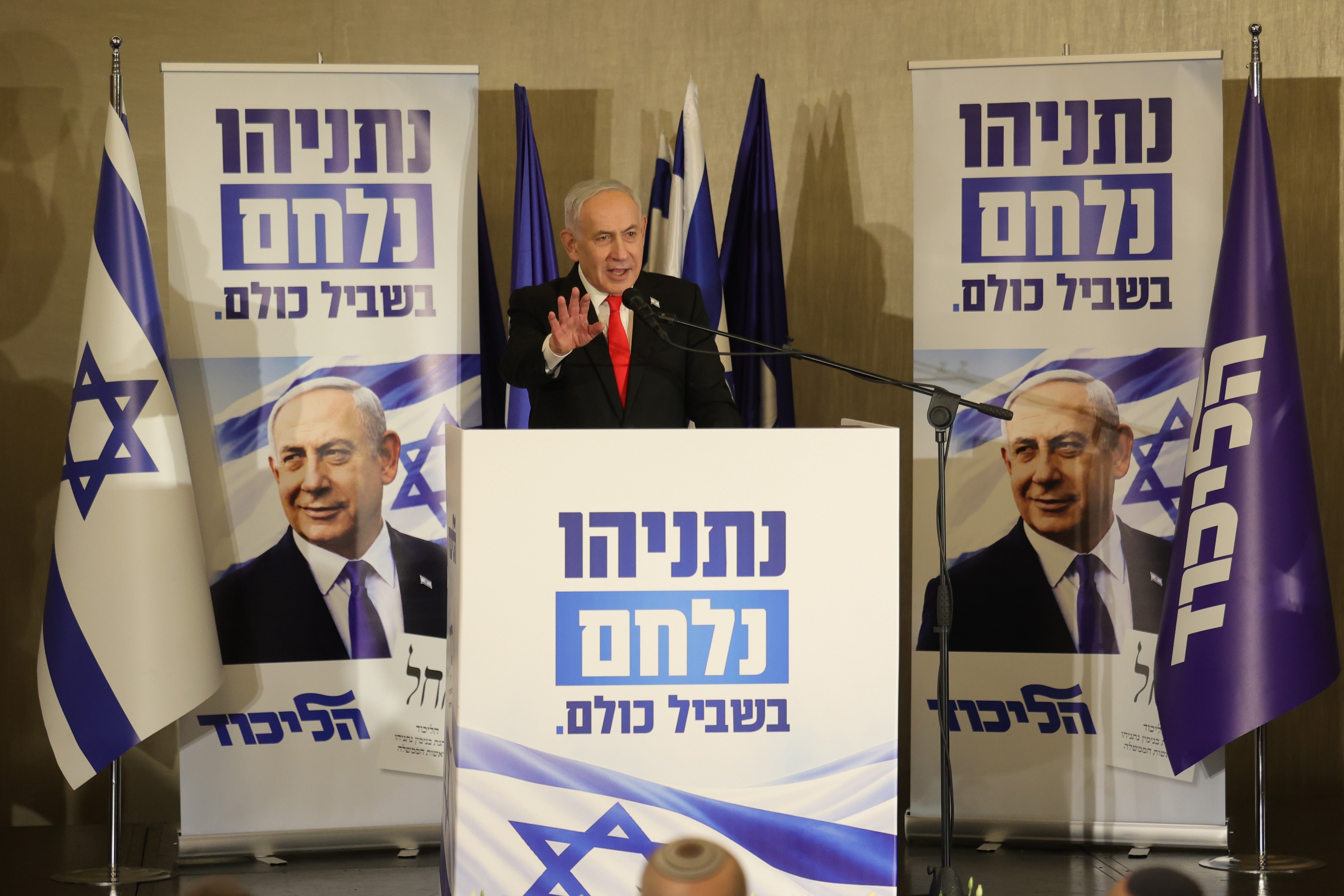 Benjamin Netanyahu speaks with election posters around him.