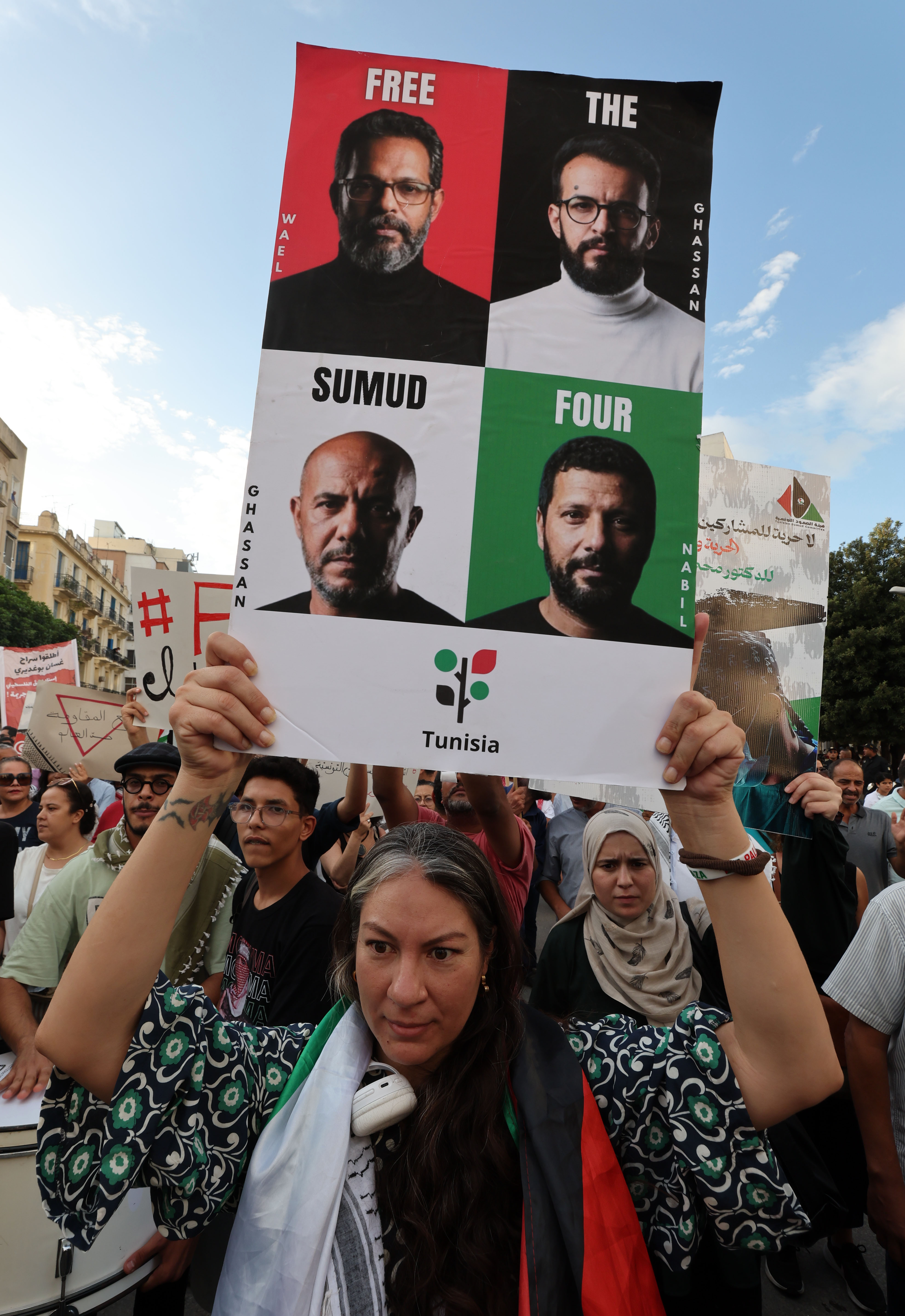 A Tunisian woman holds photos of four detained Sumud Flotilla members during a demonstration in their support in Tunis [MOHAMED MESSARA/EPA]