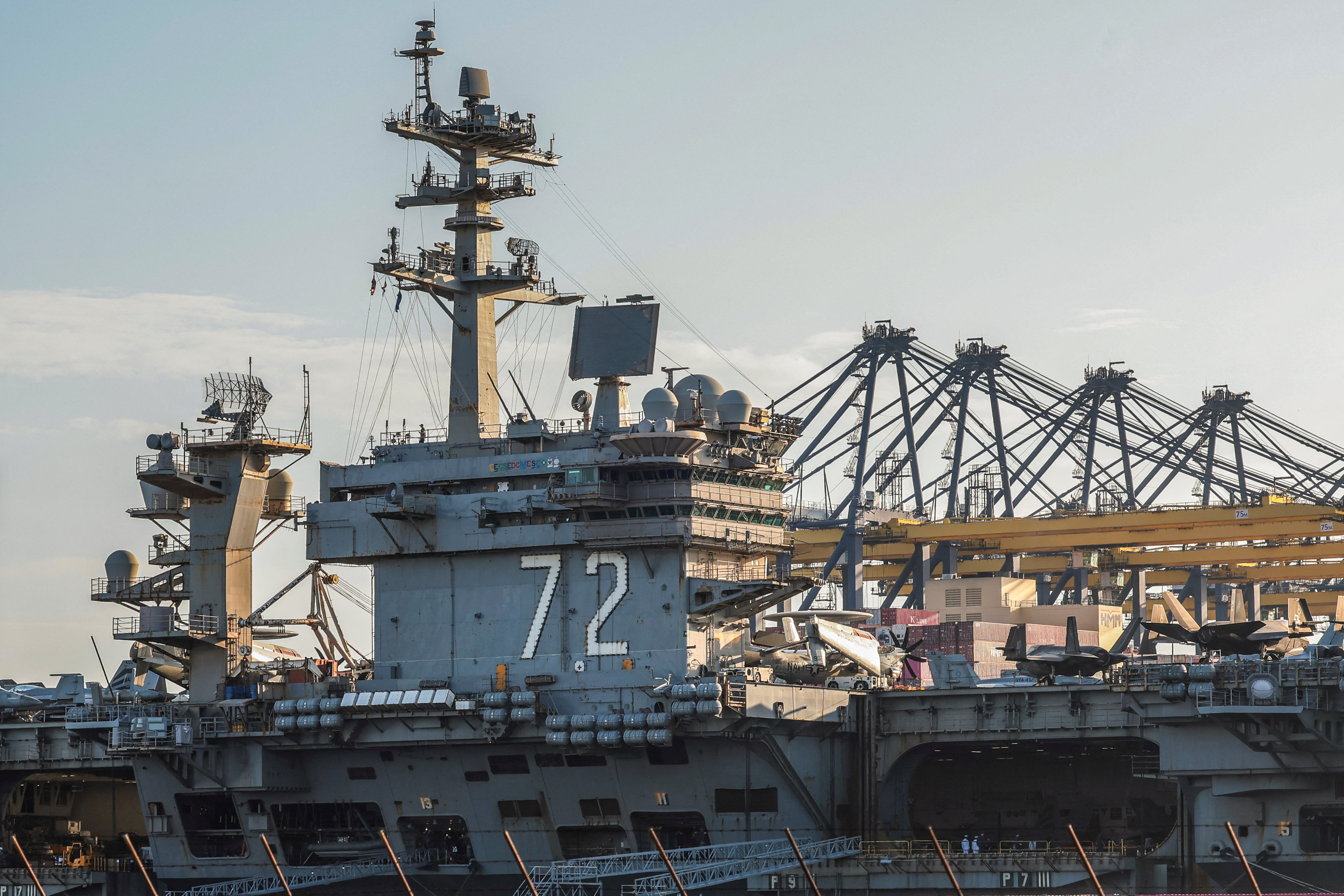 An aircraft carrier is docked at a port.