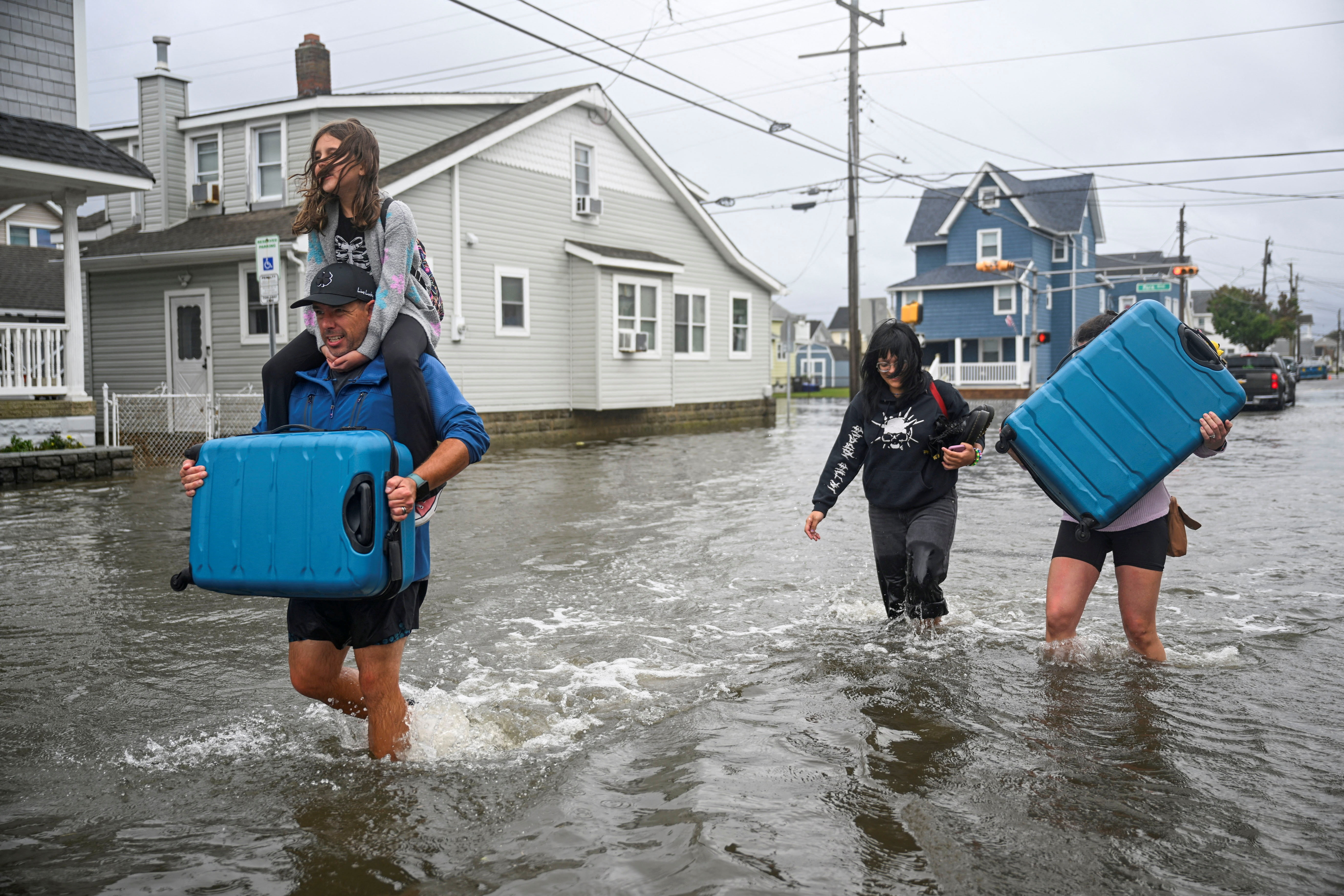 A family carrying personal belongings walks on a flooded street in Wildwood, New Jersey, US