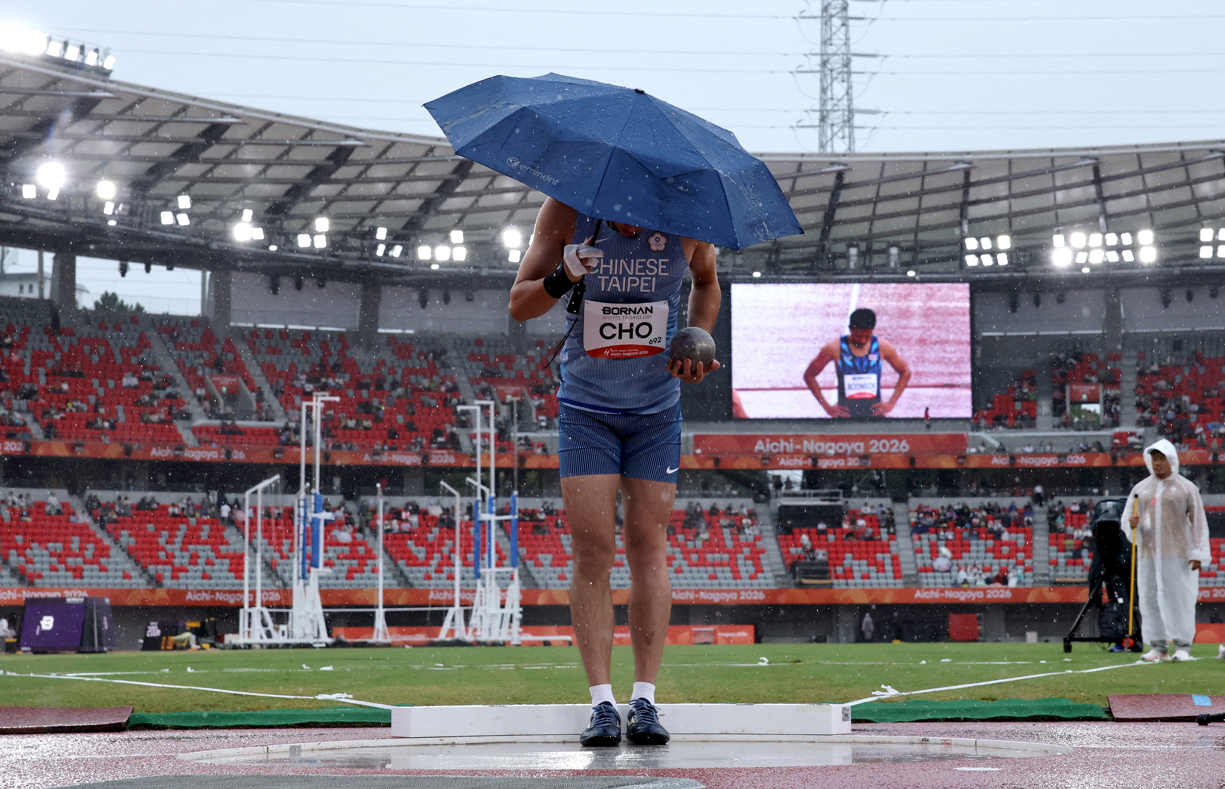 Asian Games - Aichi-Nagoya 2026 - Athletics - Paloma Mizuho Sports Park, Nagoya, Japan - September 26, 2026 Taiwan's Chia-hsuan Cho holds an umbrella just before his attempt as it rains during the Men's Decathlon Shot Put REUTERS/Andrew Boyers TPX IMAGES OF THE DAY