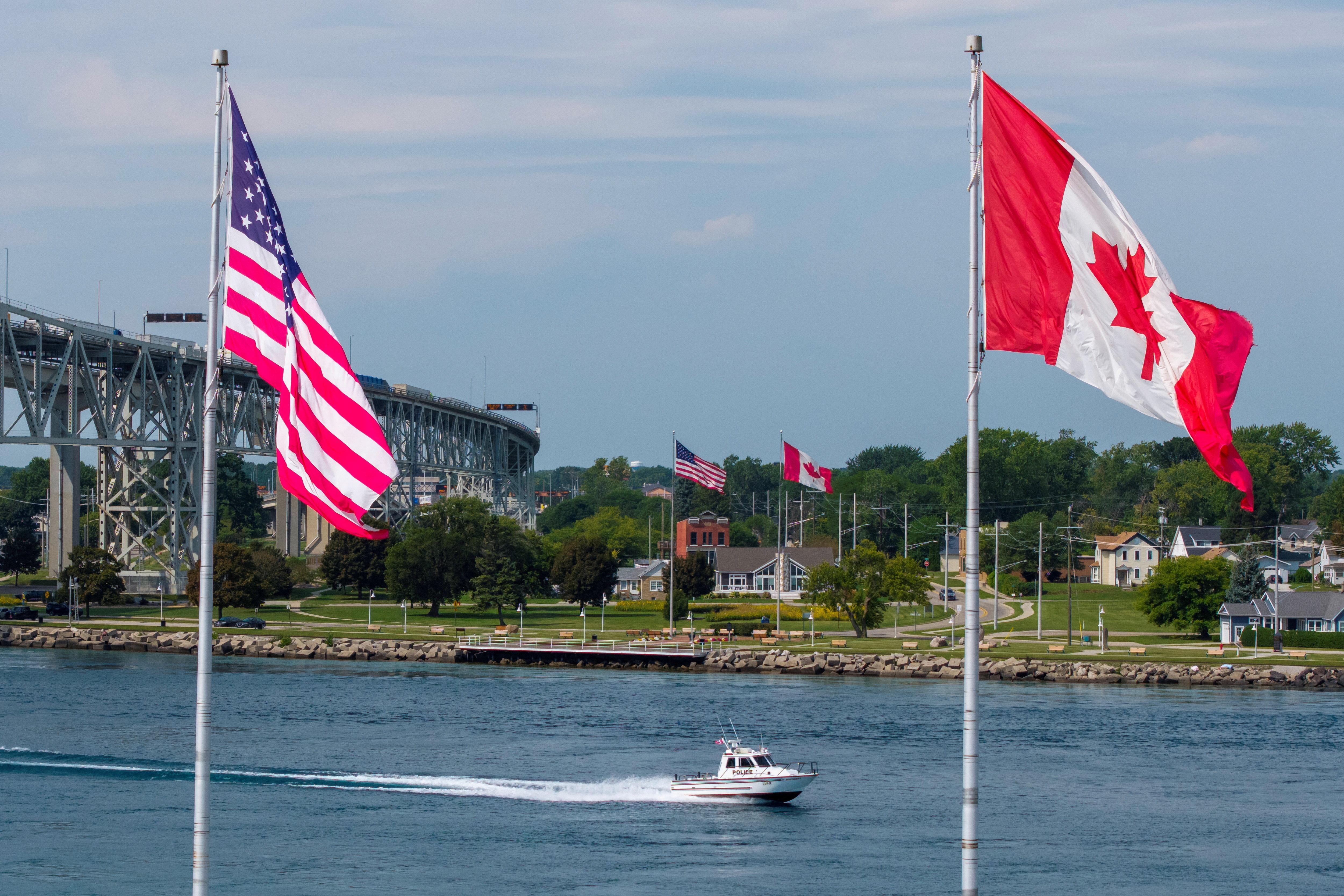 An Ontario Provincial Police boat travels along the St. Clair River as Canadian and U.S. flags fly on both sides of the border, with the Blue Water Bridge connecting Sarnia, Ontario, and Port Huron, Michigan, in the background, in Sarnia, Ontario, Canada, September 2, 2026. REUTERS/Carlos Osorio