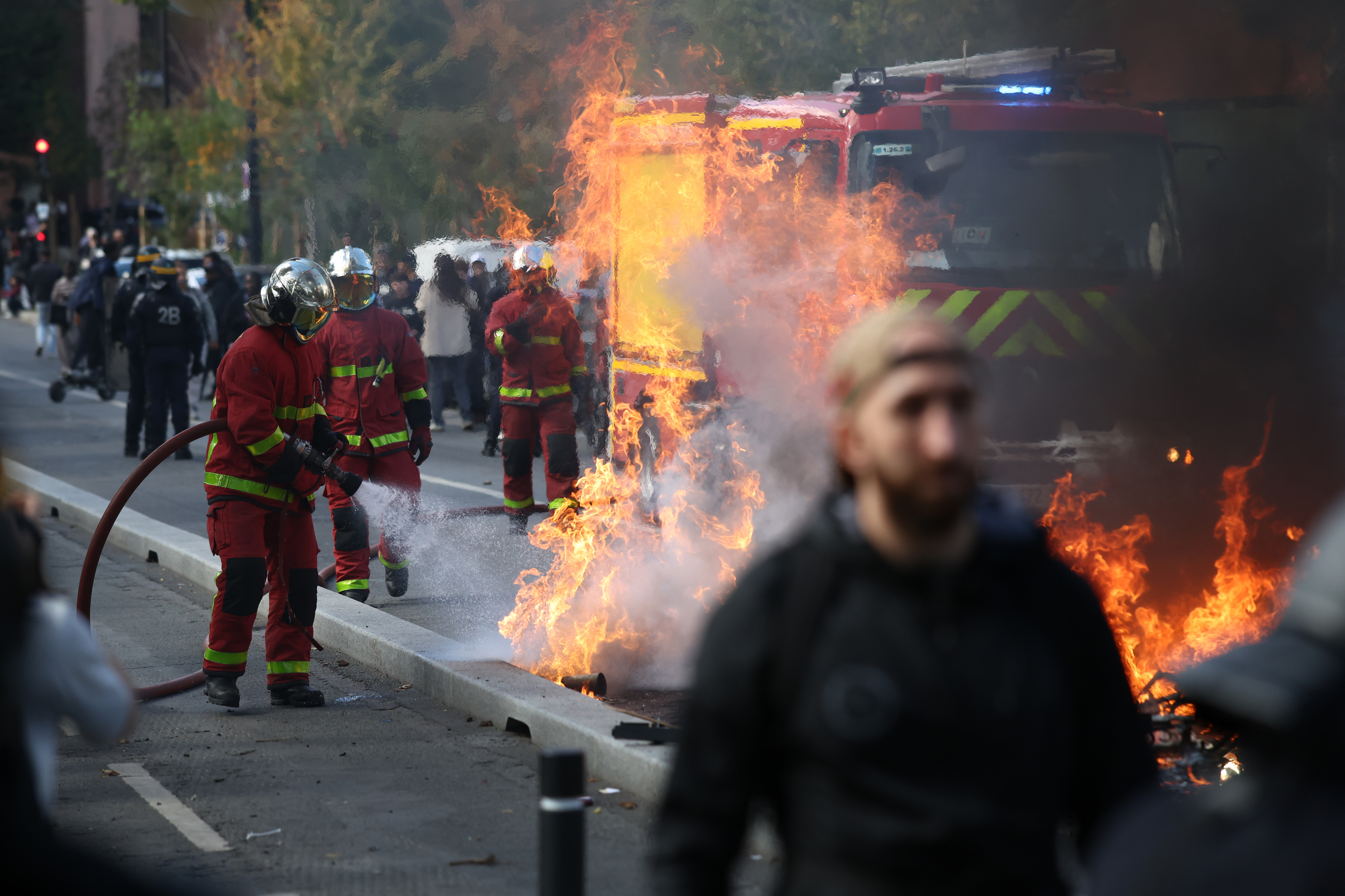 AUBERVILLIERS, FRANCE - OCTOBER 1: A fire crew puts out a fire started by French students during a march through the streets of Aubervilliers, on October 1, 2026 in Aubervilliers, a northern suburb of Paris, France. In a wave of demonstrations that began around Paris last week and spread across France, secondary students have blockaded schools in protest against overcrowded classrooms, teacher shortages, and long class schedules. According to French Interior Minister Laurent Nunez, more than 400 have been detained, many of them minors, as some protests turned violent where students and police clashed. (Photo by Tom Nicholson/Getty Images)